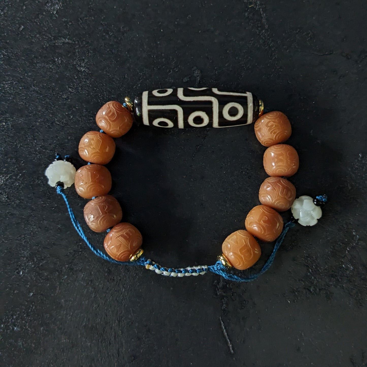 Un bracelet en perles avec mantras et avec une perles Dzi à neuf yeux