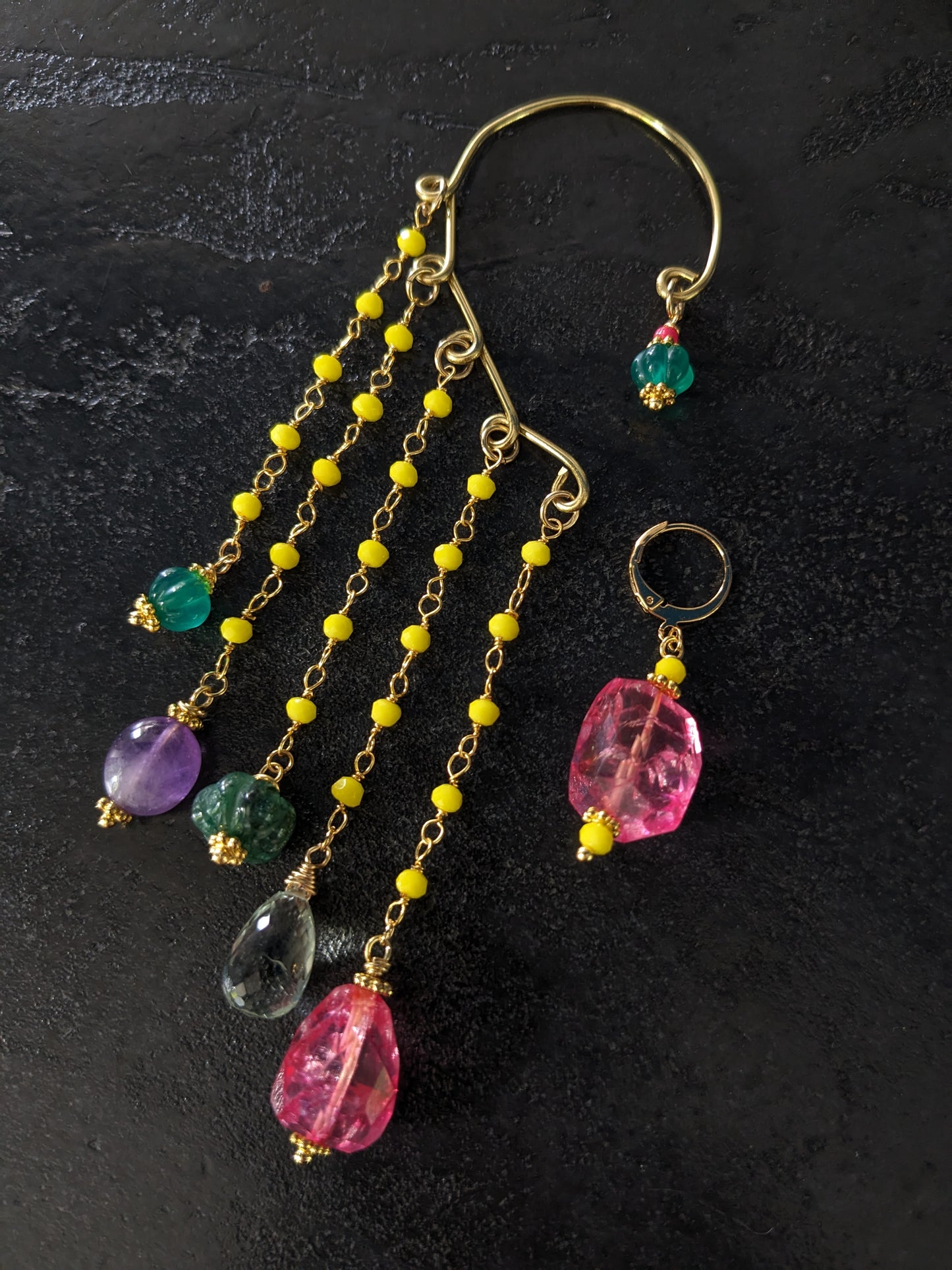 Boucles d'oreilles 'Goa' méticuleusement conçues, mettant en vedette une gravure sur onyx vert, des pierres d'agate teintées en rose, des gemmes d'améthyste et d'améthyste verte, complétées par des chaînes ornées de cristaux étincelants. Un hommage vibrant aux couleurs de l'Inde