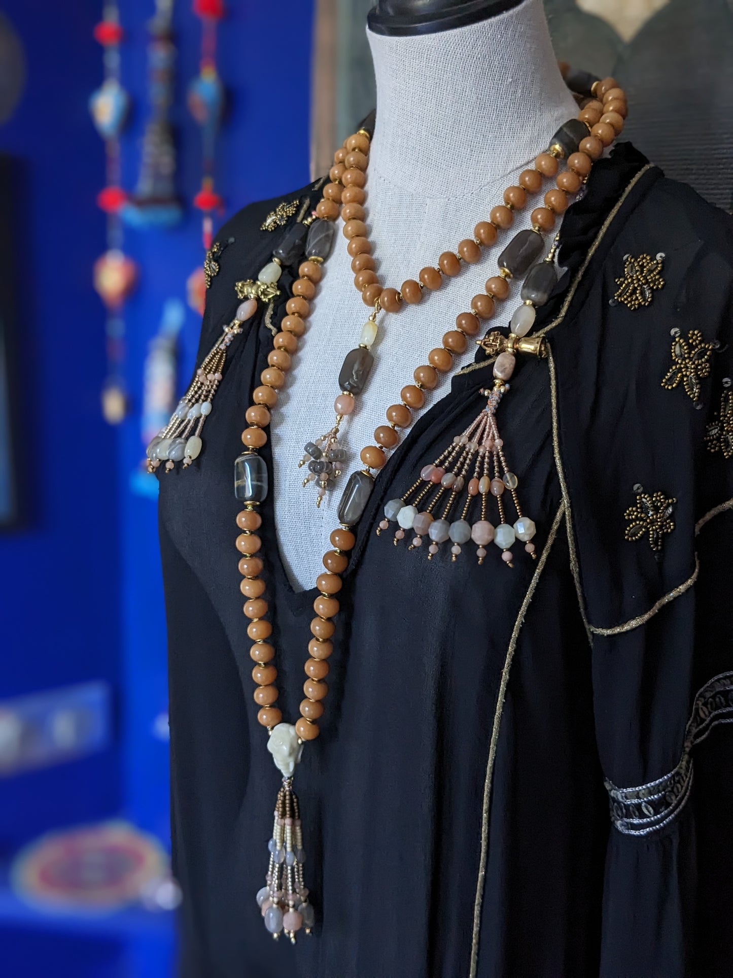 Image d'un magnifique collier Mala Ayodhya, soigneusement placé sur une surface en bois rustique sous une lumière douce et chaleureuse, mettant en valeur ses perles de racine de Bodhi miel naturelles et ses perles de pierre de lune grise. Le design complexe et le savoir-faire artisanal du collier sont mis en évidence.