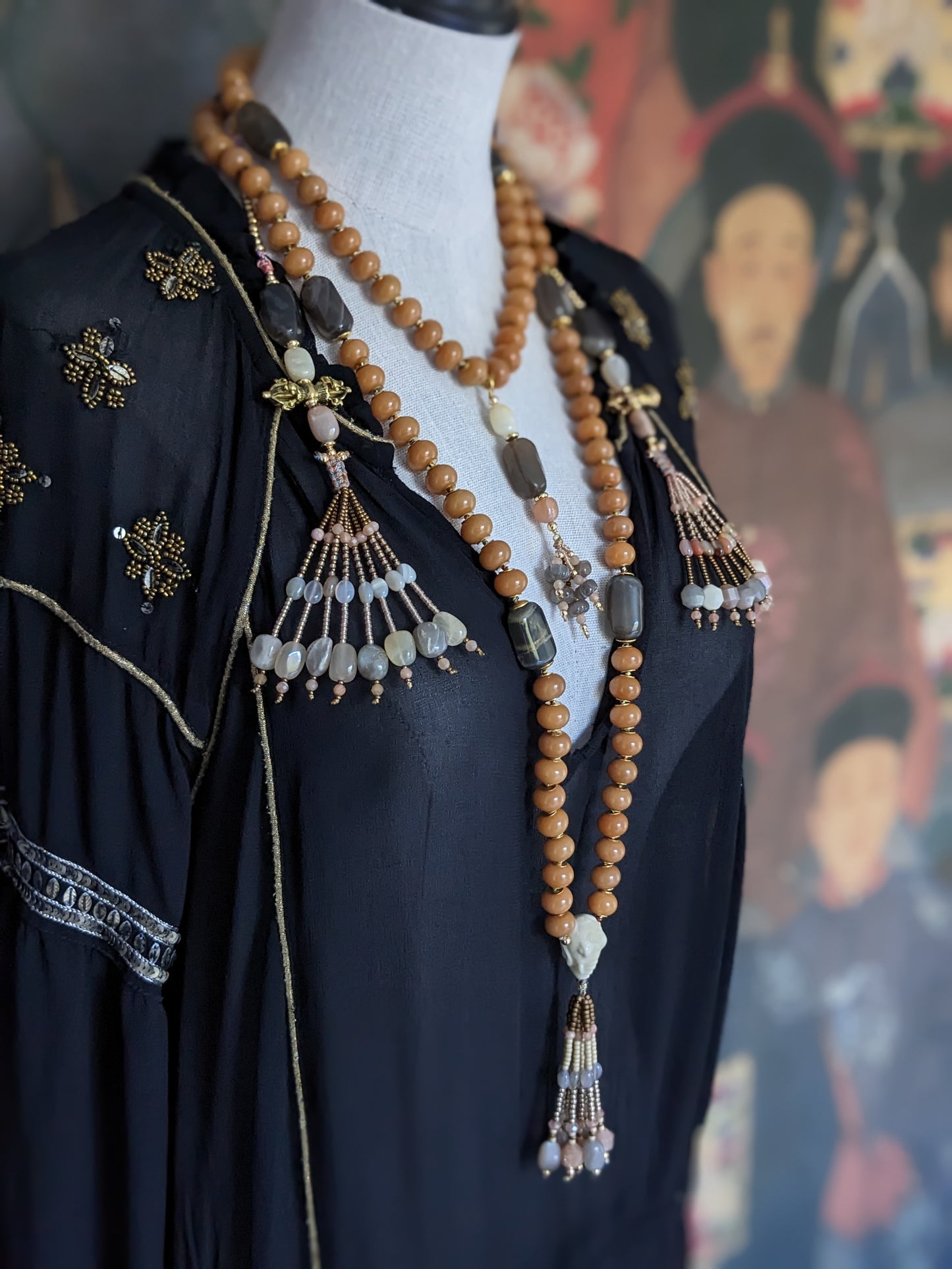 Image d'un magnifique collier Mala Ayodhya, soigneusement placé sur une surface en bois rustique sous une lumière douce et chaleureuse, mettant en valeur ses perles de racine de Bodhi miel naturelles et ses perles de pierre de lune grise. Le design complexe et le savoir-faire artisanal du collier sont mis en évidence.