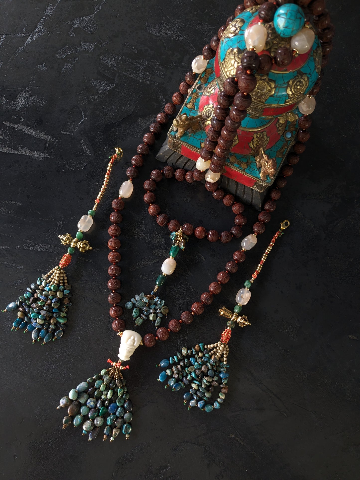 Image captivante du Mala Shambhala, un collier de méditation unique, mettant en valeur ses perles naturelles multicolores et ses compteurs de style tibétain, le tout évoquant une sensation de tranquillité et de profondeur spirituelle.