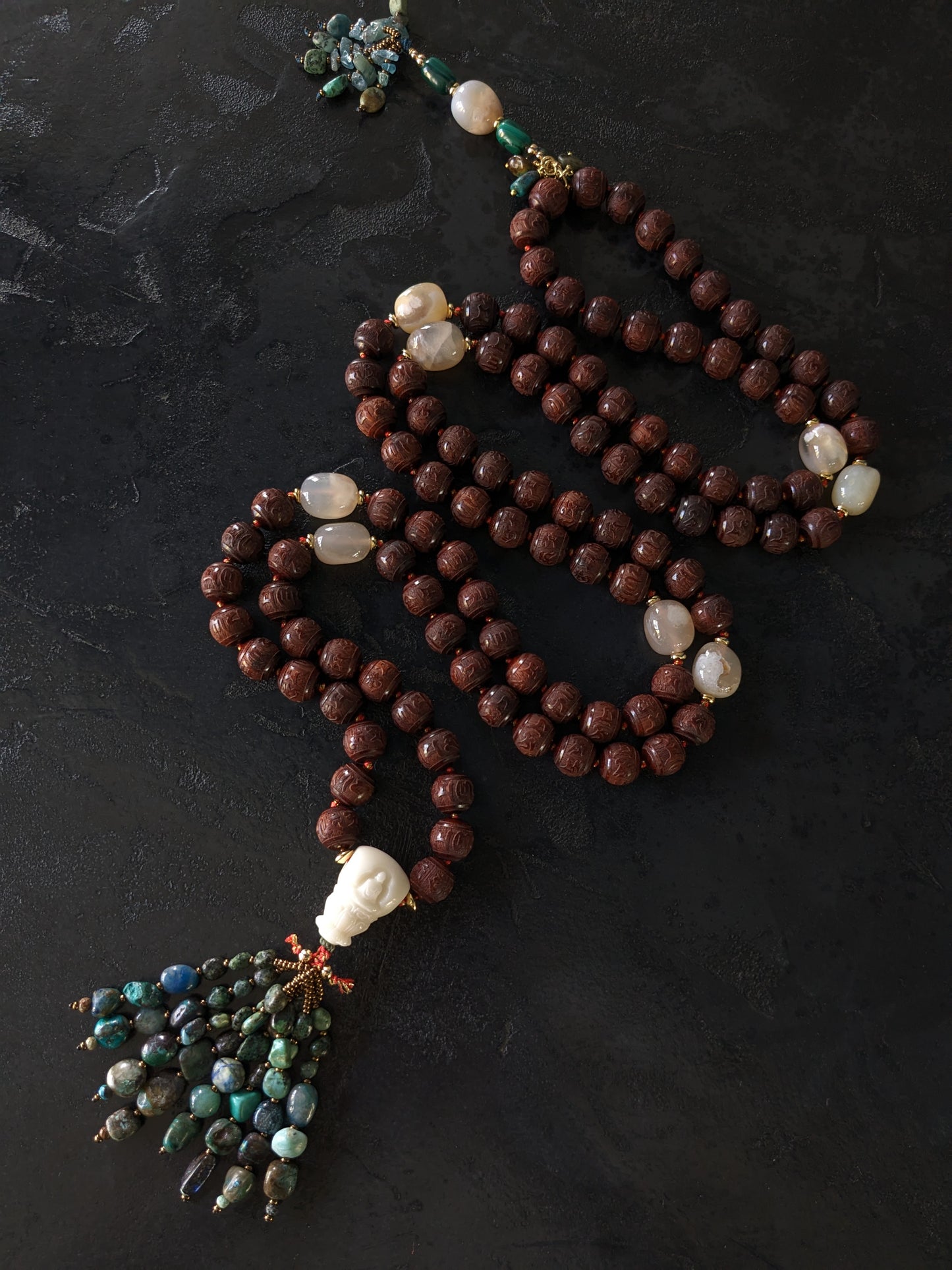 Image captivante du Mala Shambhala, un collier de méditation unique, mettant en valeur ses perles naturelles multicolores et ses compteurs de style tibétain, le tout évoquant une sensation de tranquillité et de profondeur spirituelle.