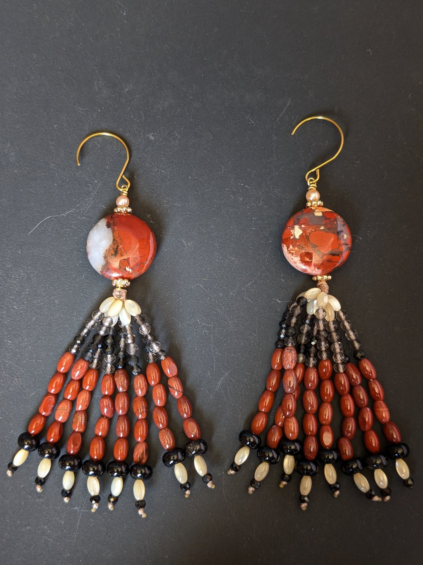 Paire de pendants d'oreilles Ojal posée à plat, jaspe rouge, quartz fumé, onyx et nacre de trochus