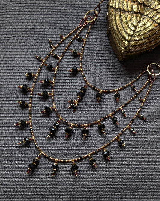 Collier trois rangs en onyx noir, obsidienne et tourmaline noire, ponctué de grenat rouge sombre, avec franges de rocailles japonaises or et bordeaux, pièce unique, élégant et sophistiqué.