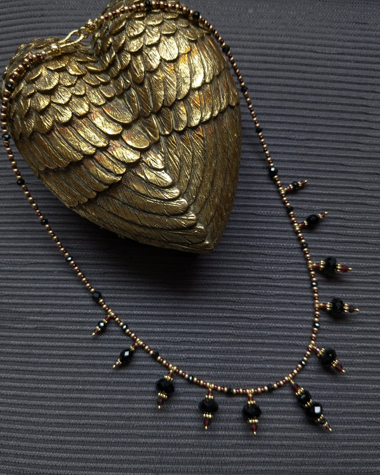 Collier Onyx et Grenat, franges d’onyx noir facetté, tourmaline noire, obsidienne et éclats de grenat rouge sombre, rocailles japonaises bronze et bordeaux, pièce unique élégante et subtile.