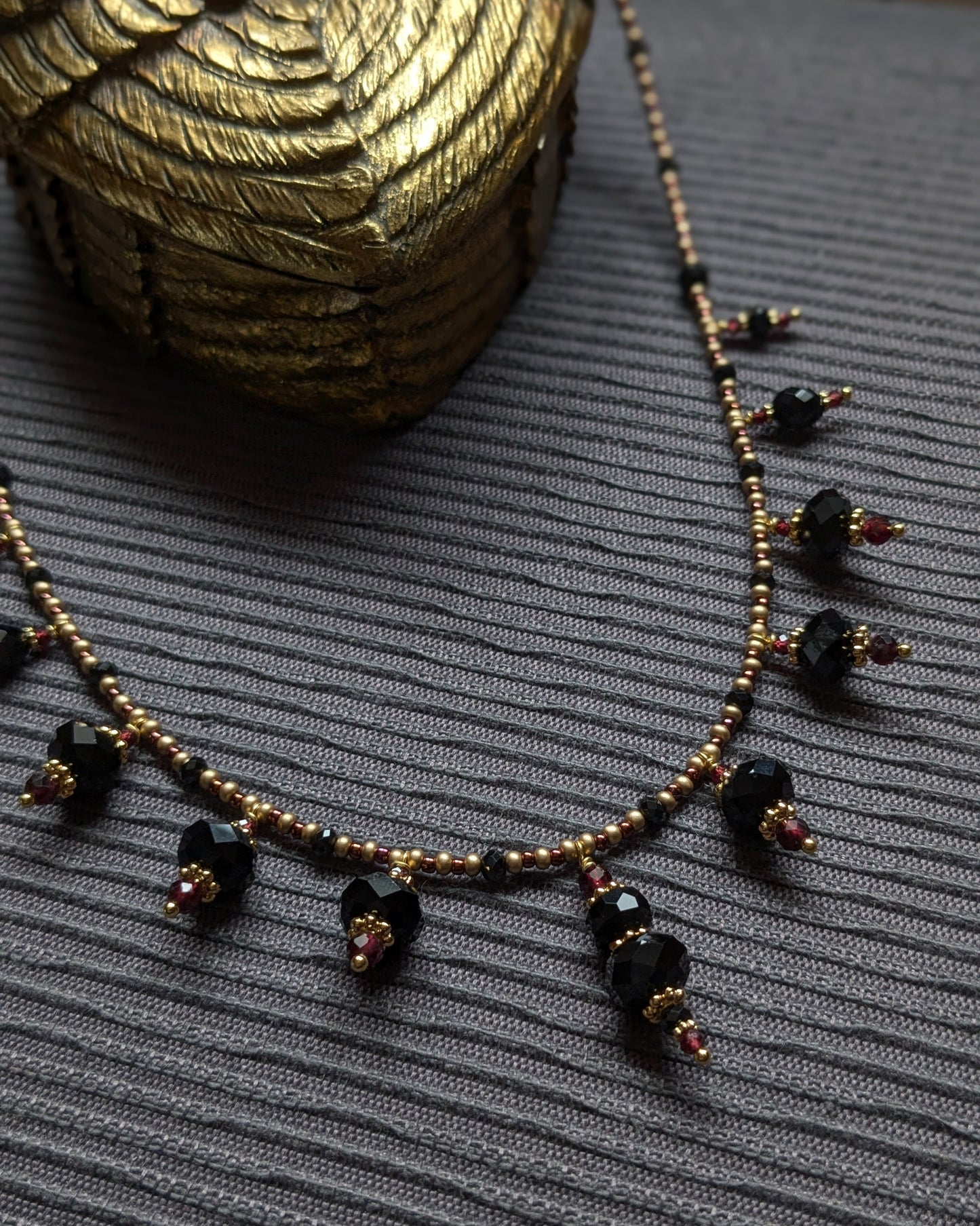 Contrastes entre l'éclat métallique du spinelle noir, la profondeur de l'obsidienne et les reflets du grenat sombre.
