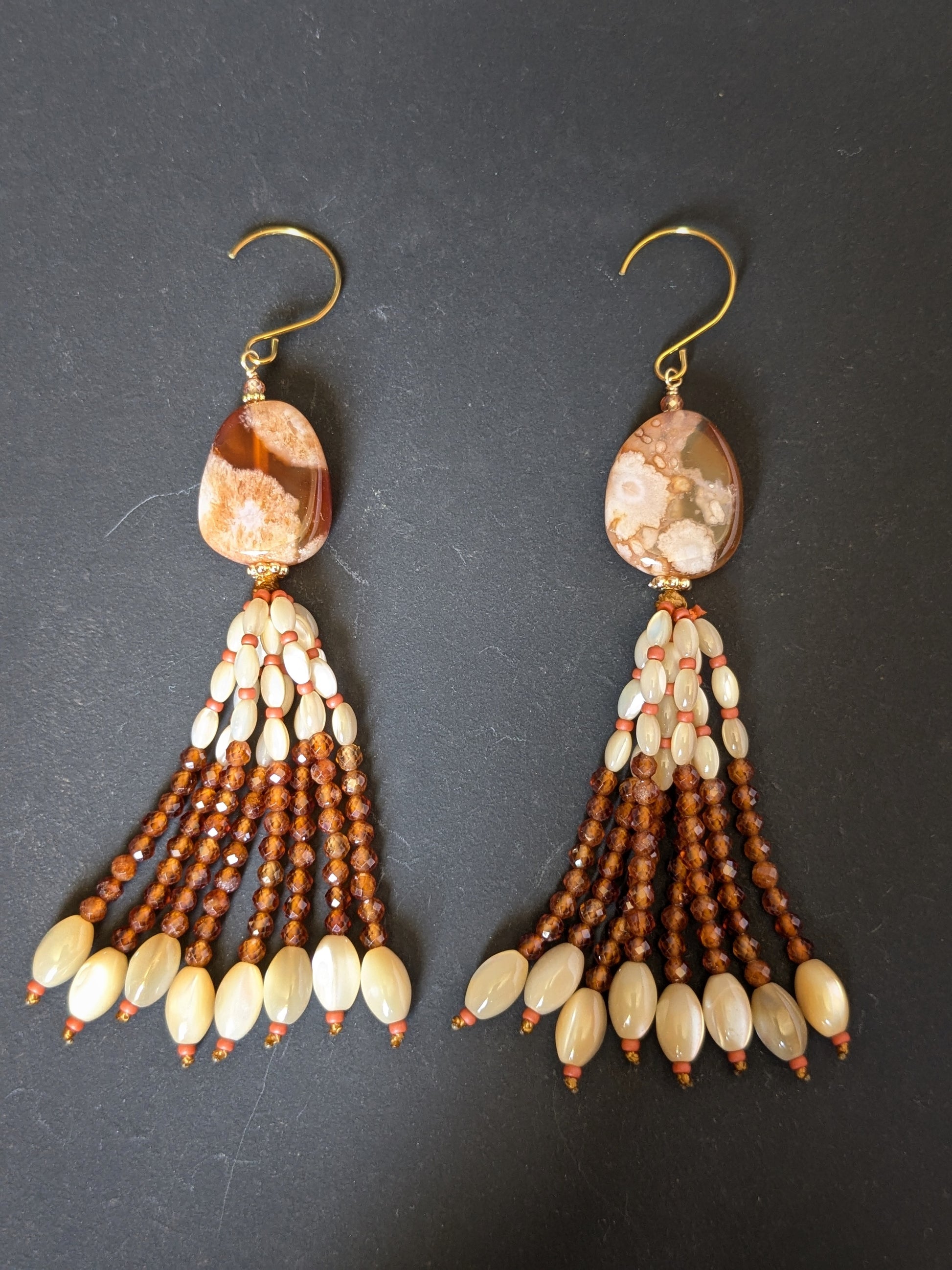 Pendants d'oreilles Chameli posés sur un présentoir, inclusions marquées de l'agate sakura
