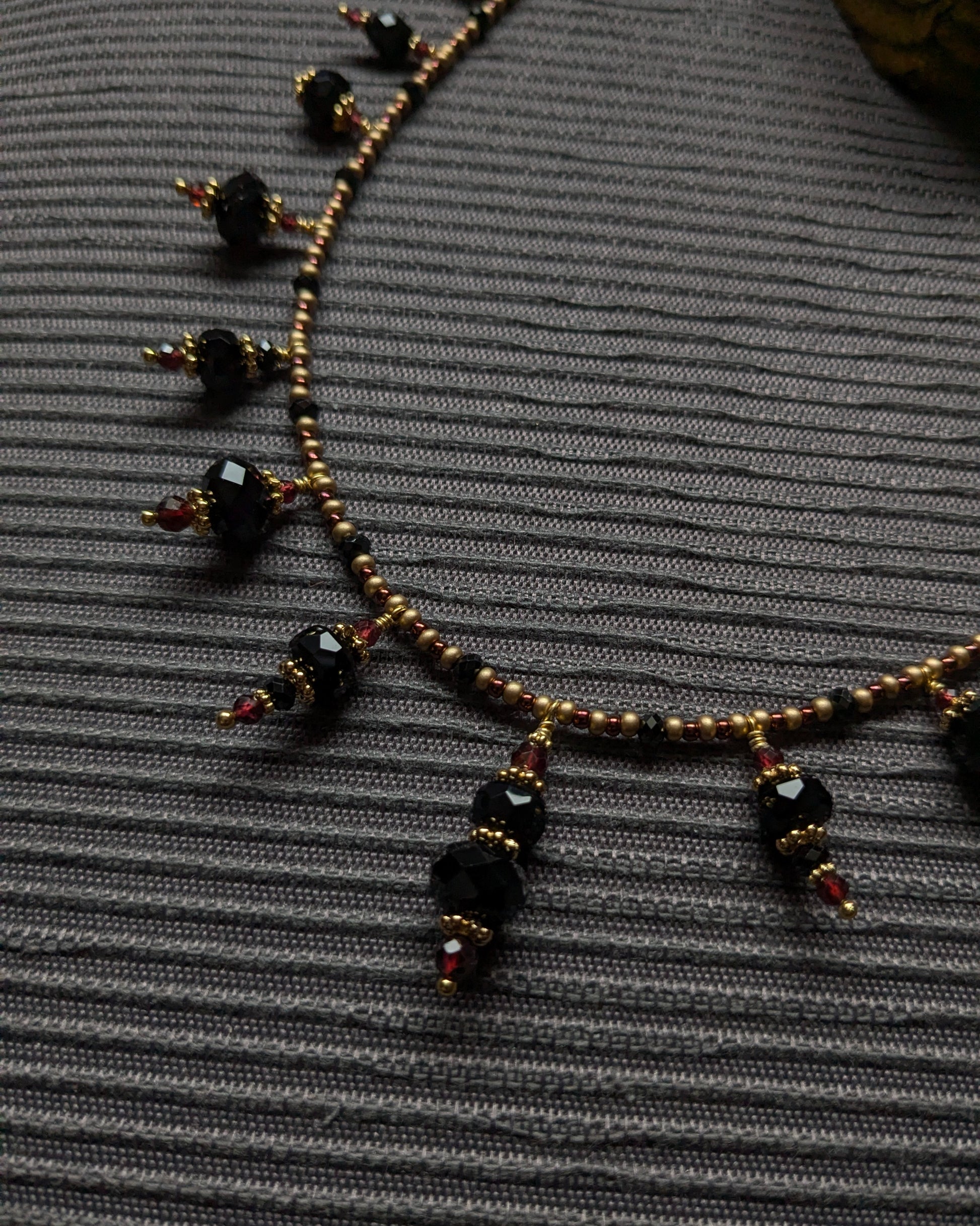 Mouvement discret des breloques minérales noires montées sur laiton doré à patine douce.