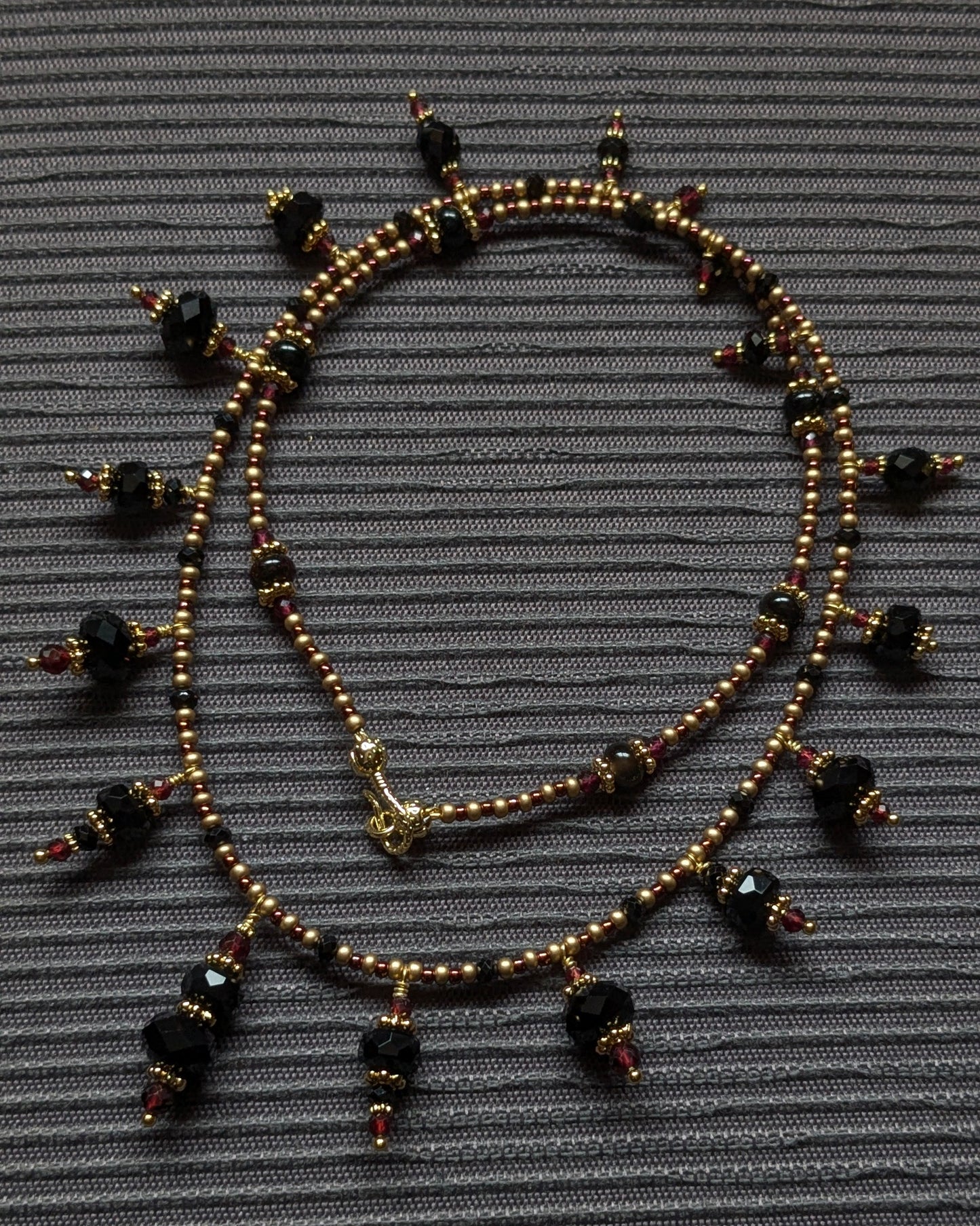 Détail des surfaces contrastées de l'onyx facetté et de la tourmaline brute sur le collier Chayara.