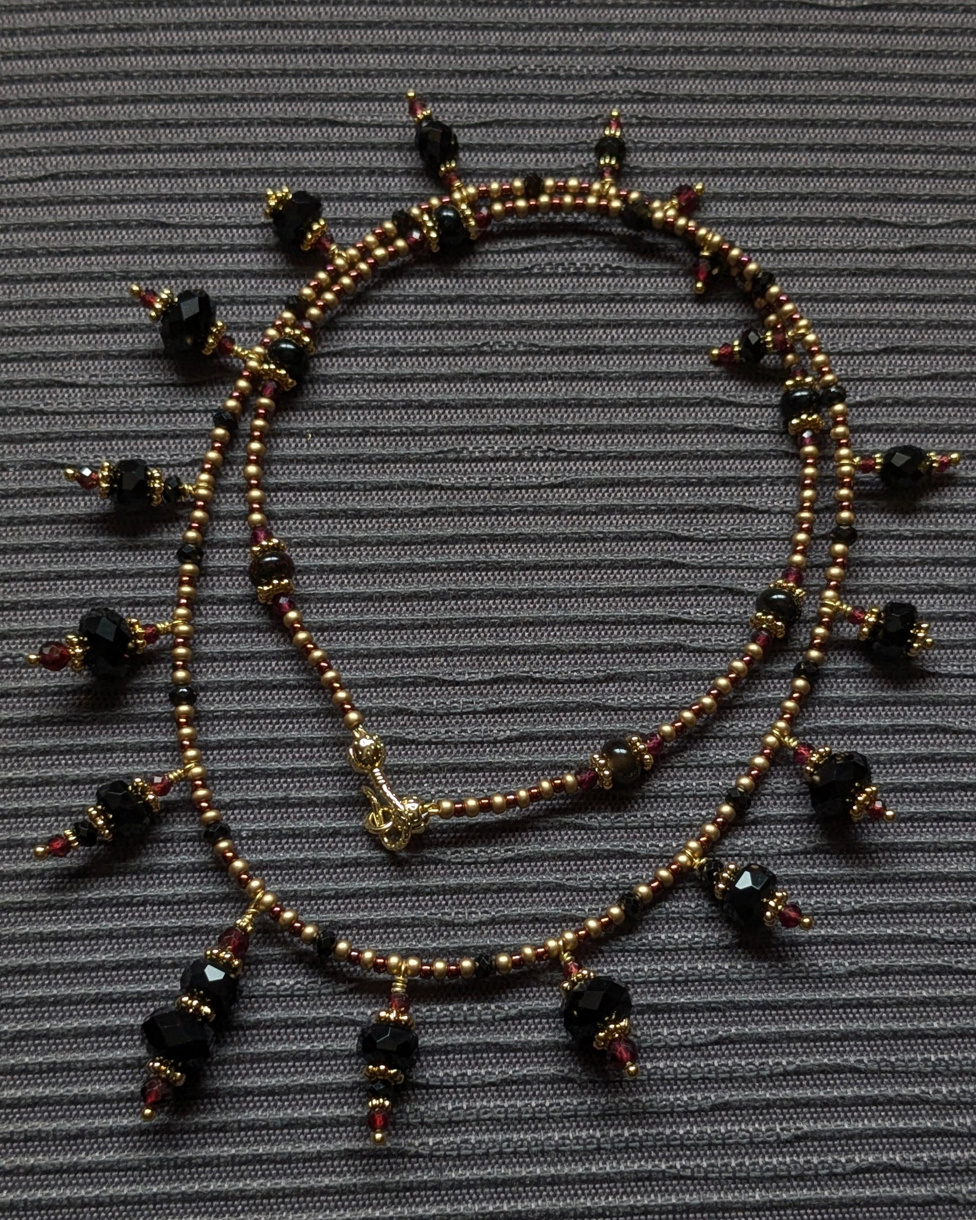 Détail des surfaces contrastées de l'onyx facetté et de la tourmaline brute sur le collier Chayara.