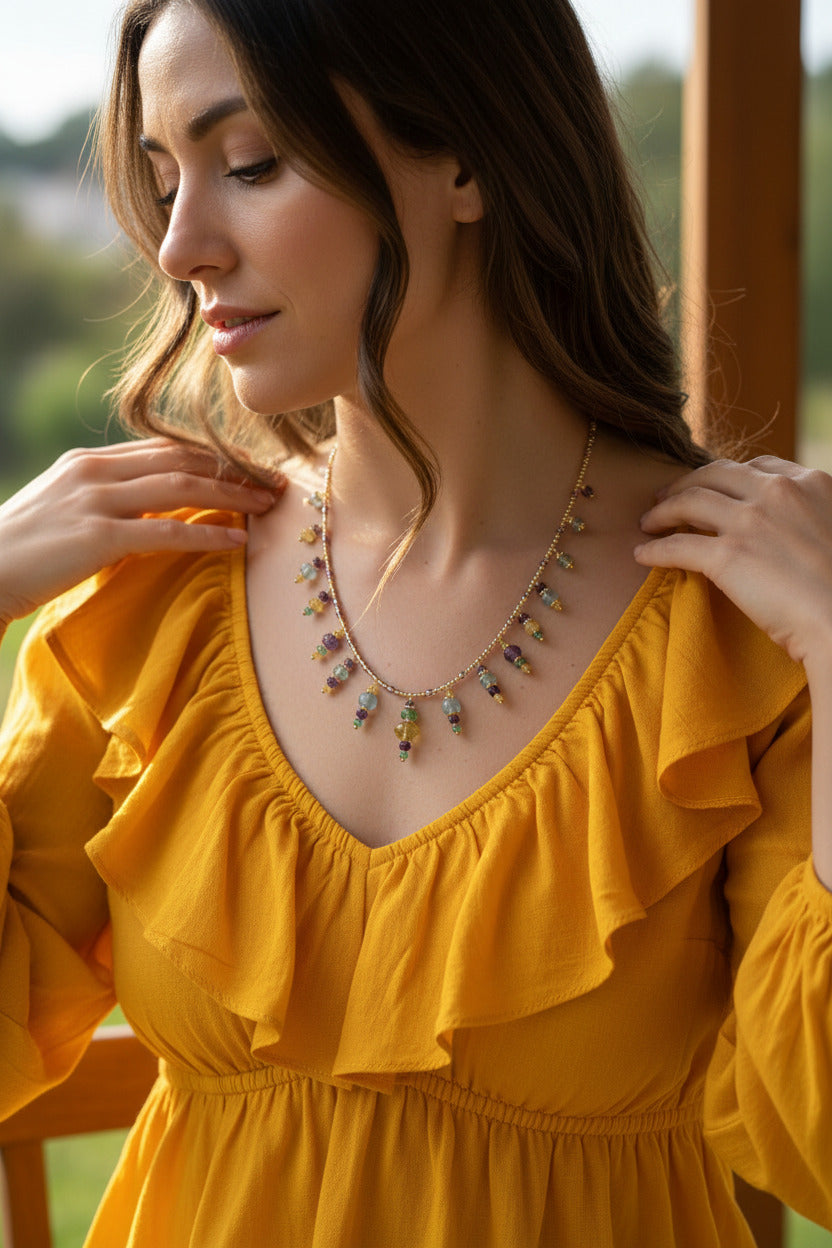 Le collier Devisha porté au sternum, illustrant sa ligne aérienne et ses nuances de violet et vert.