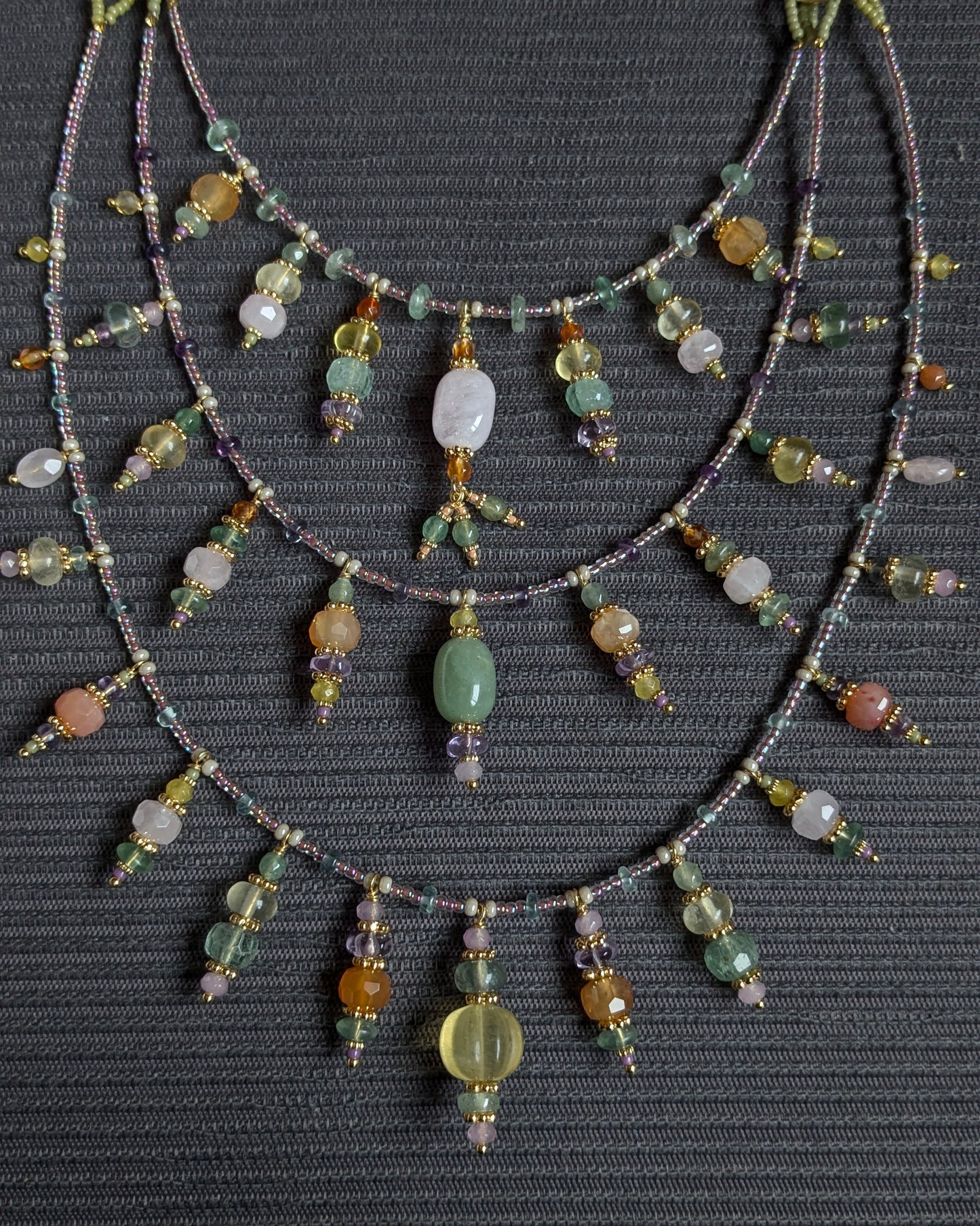 Détail de la morganite ovale rosée et des anneaux dorés structurant le collier Fayali.