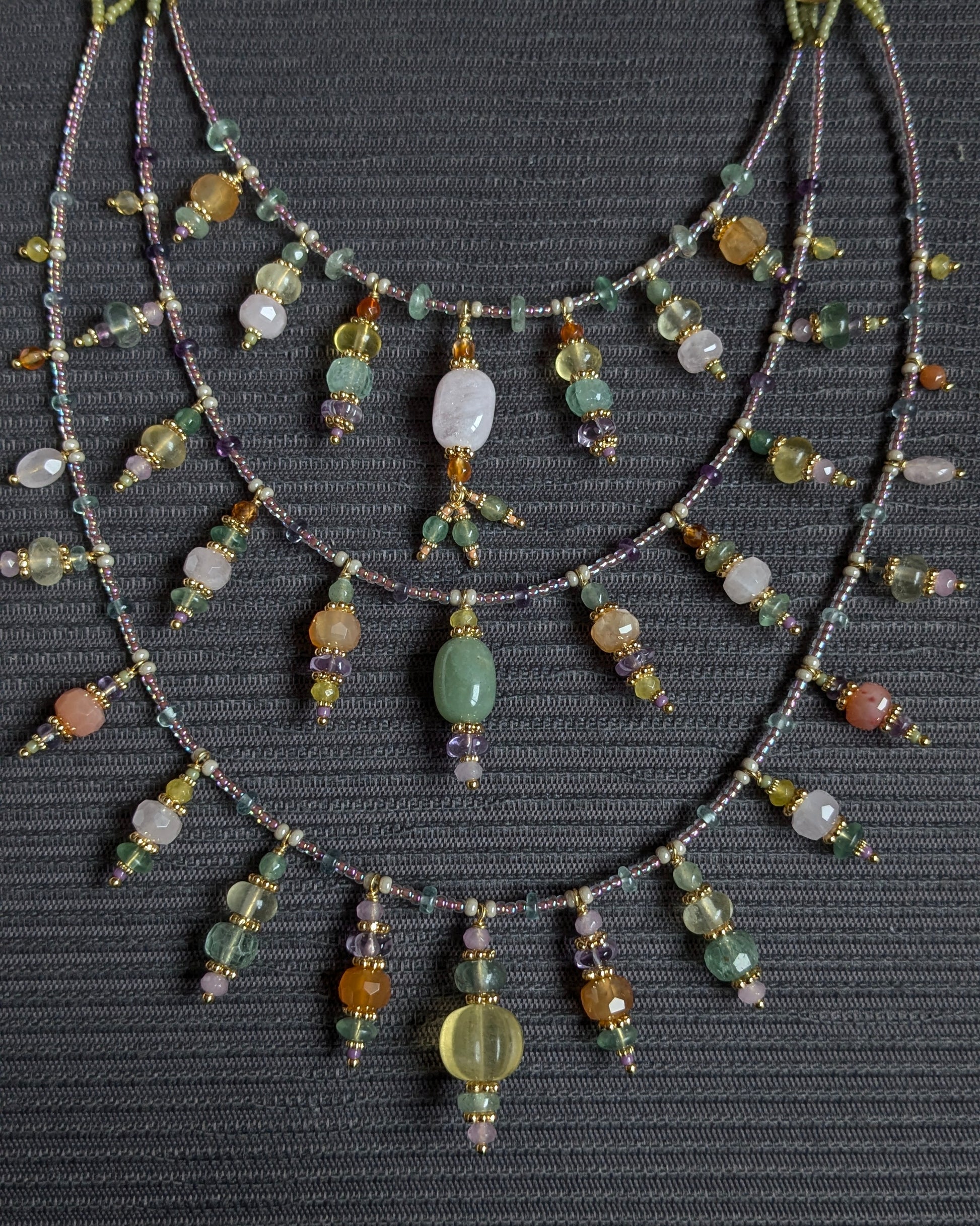 Détail de la morganite ovale rosée et des anneaux dorés structurant le collier Fayali.
