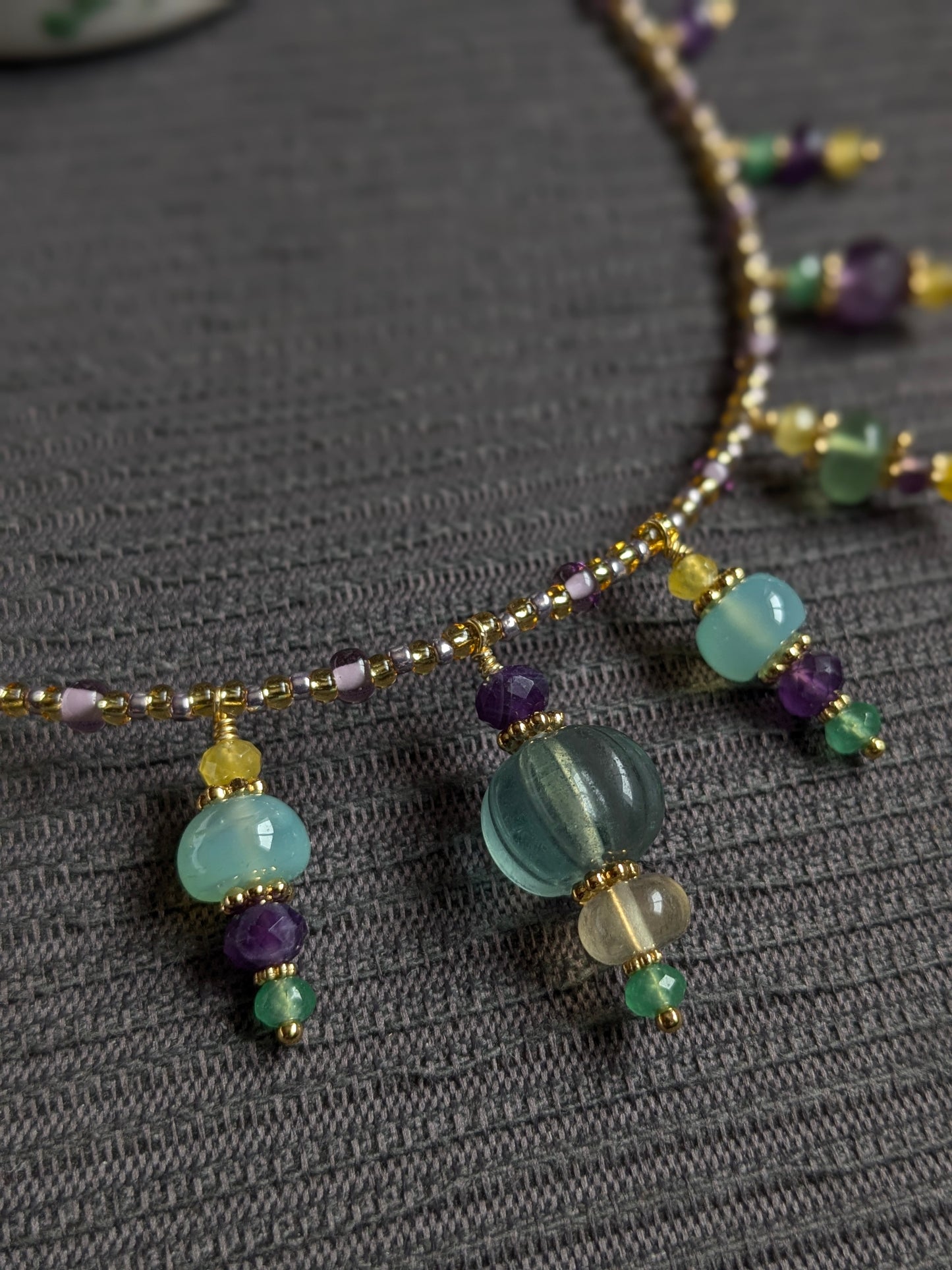 Détail des facettes de la fluorite verte et de la texture mate du jade jaune sur le collier artisanal.