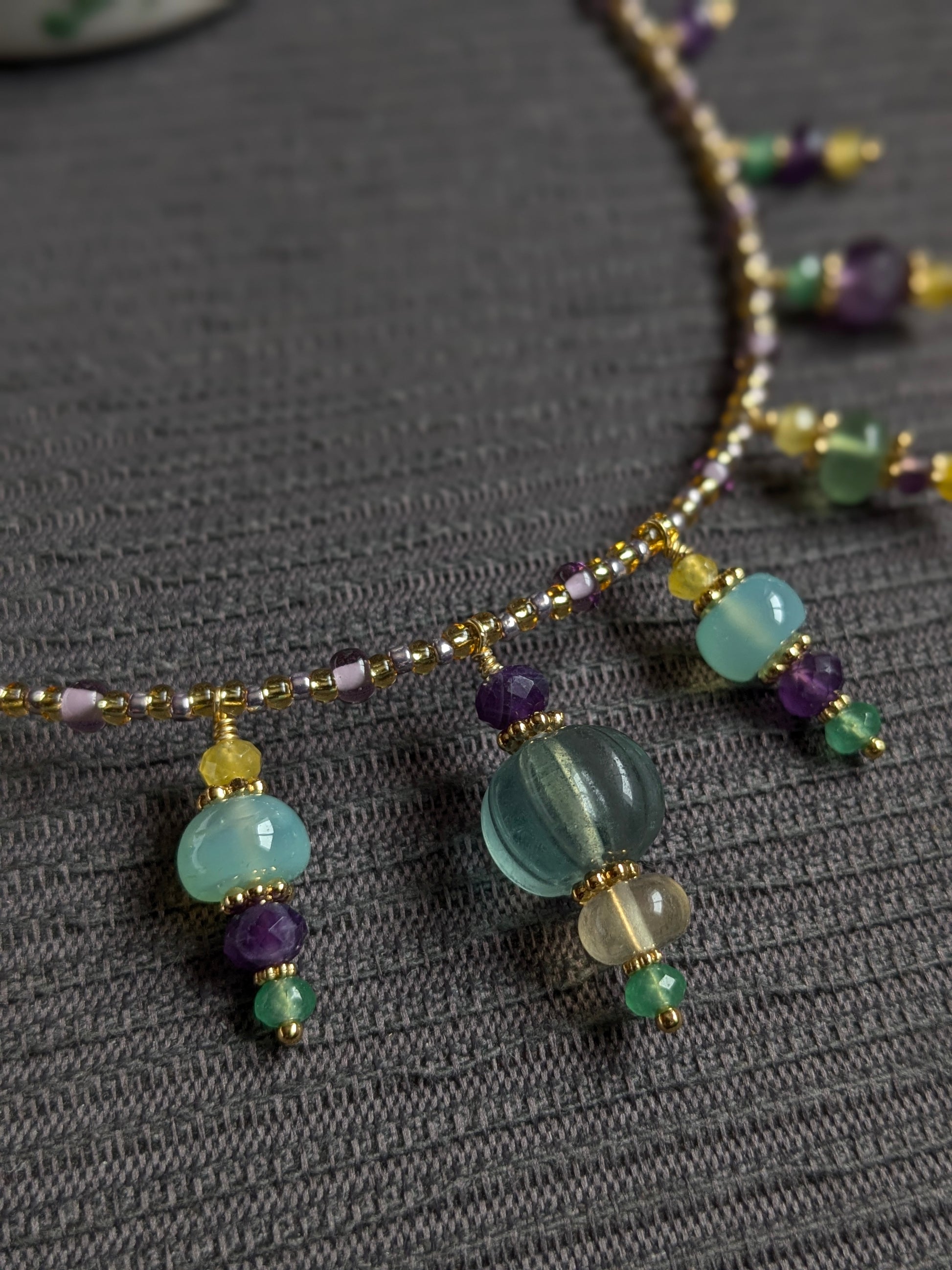 Détail des facettes de la fluorite verte et de la texture mate du jade jaune sur le collier artisanal.