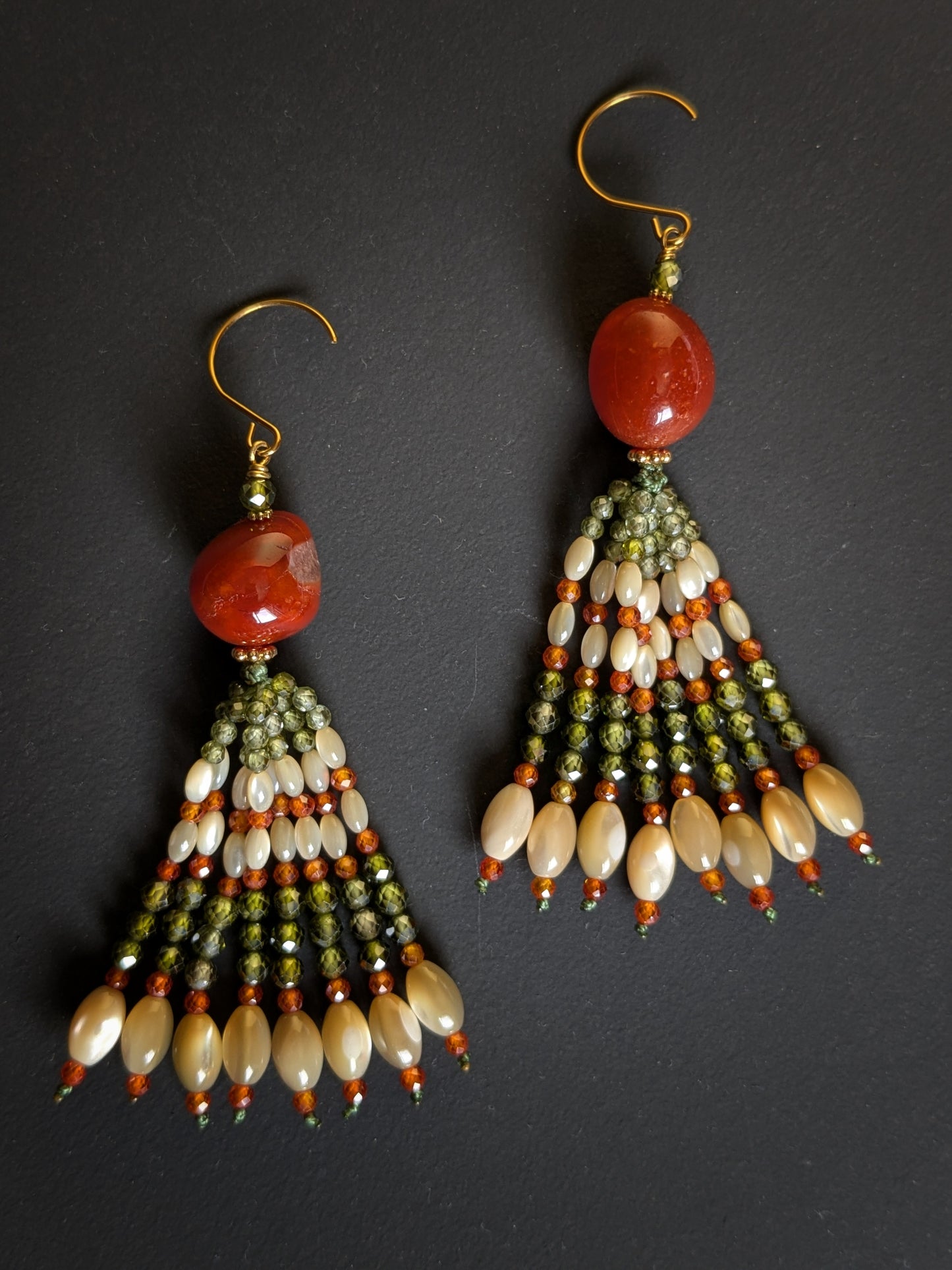 Paire de pendants d'oreilles Kiran posée à plat, zircons cubiques verts et orange et nacre de trochus