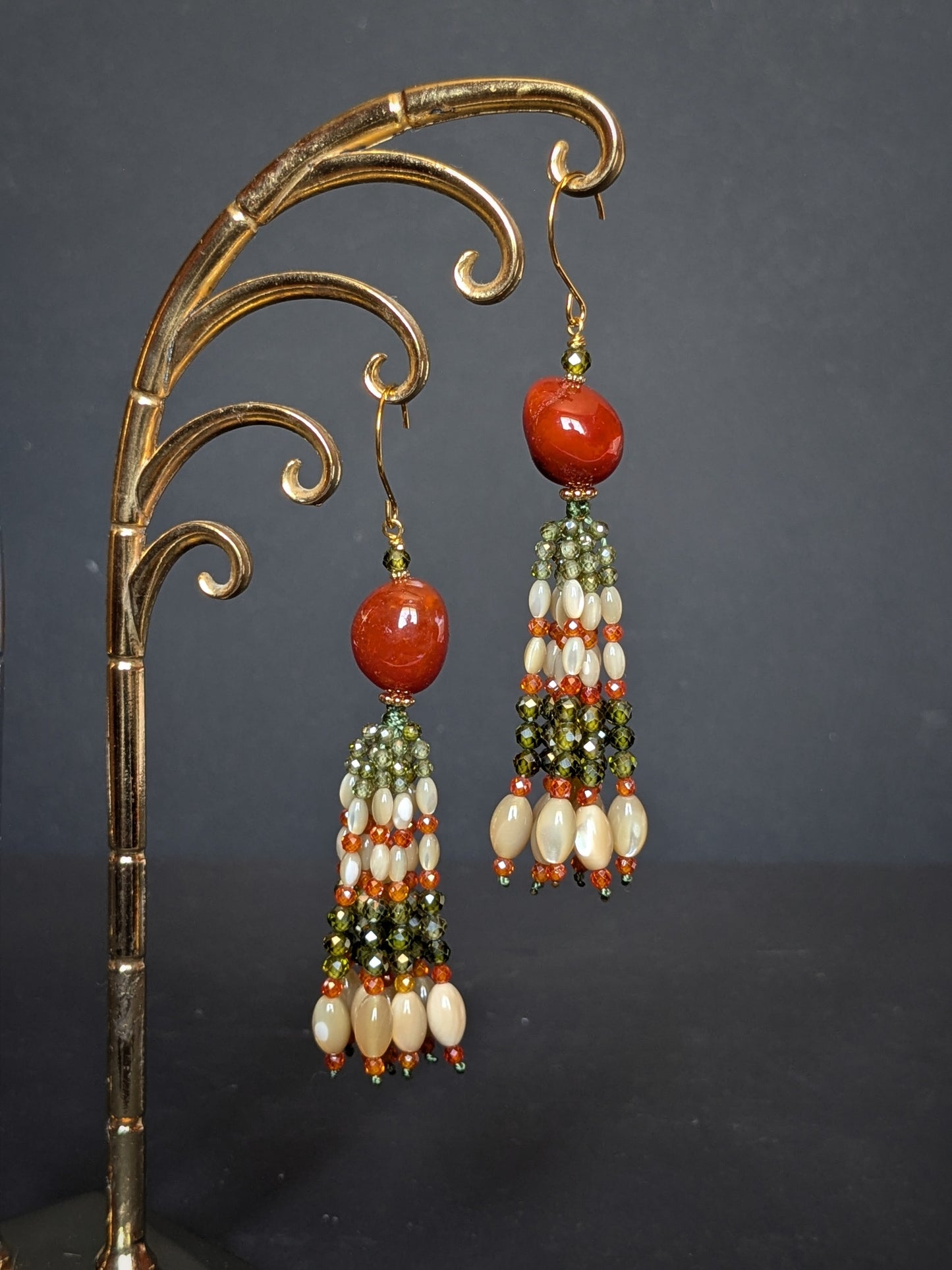 Pendants d'oreilles Kiran posés sur un présentoir, agate du Botswana et tassel vert et orange