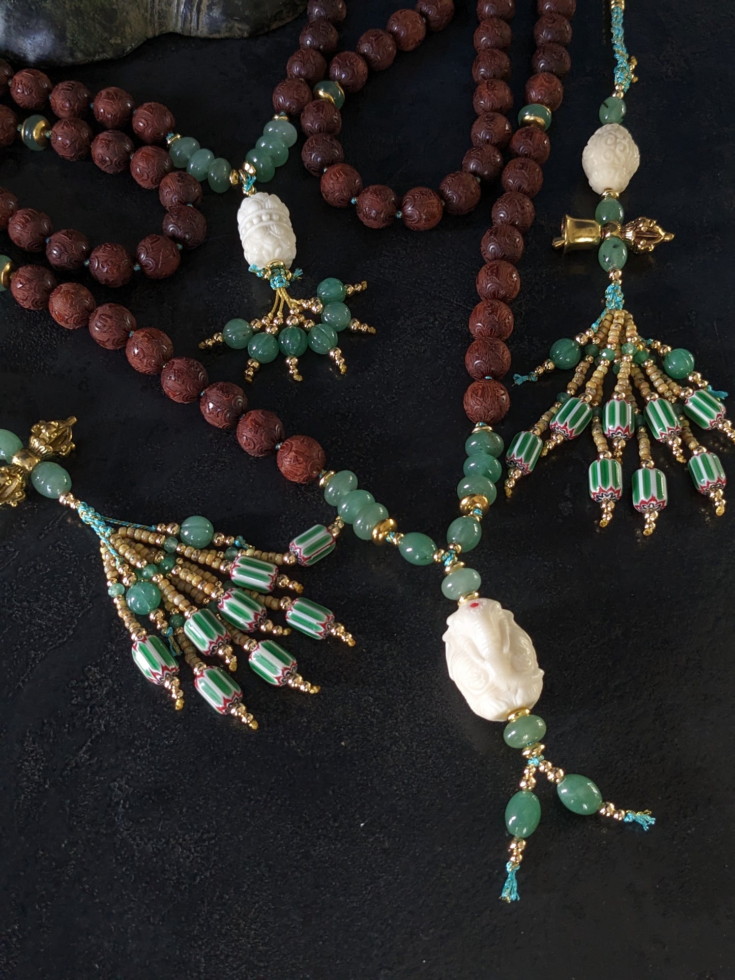 Chapelet bouddhiste Mala Kanchipuram artisanal, orné de perles d'aventurine vertes éclatantes et de bois de santal rouge riche. Un bijou spirituel unique qui respire la chaleur et le savoir-faire.