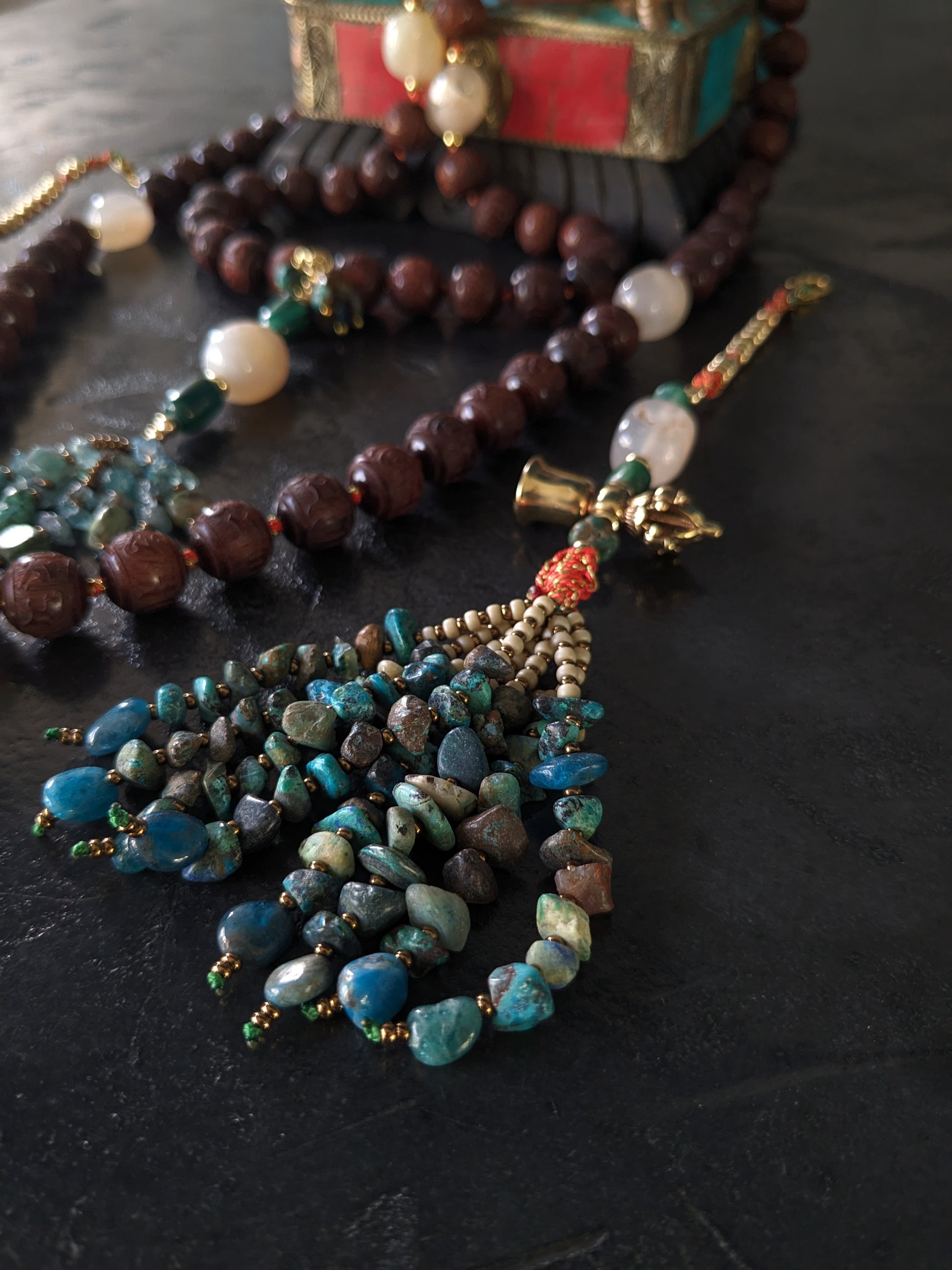 Image captivante du Mala Shambhala, un collier de méditation unique, mettant en valeur ses perles naturelles multicolores et ses compteurs de style tibétain, le tout évoquant une sensation de tranquillité et de profondeur spirituelle.