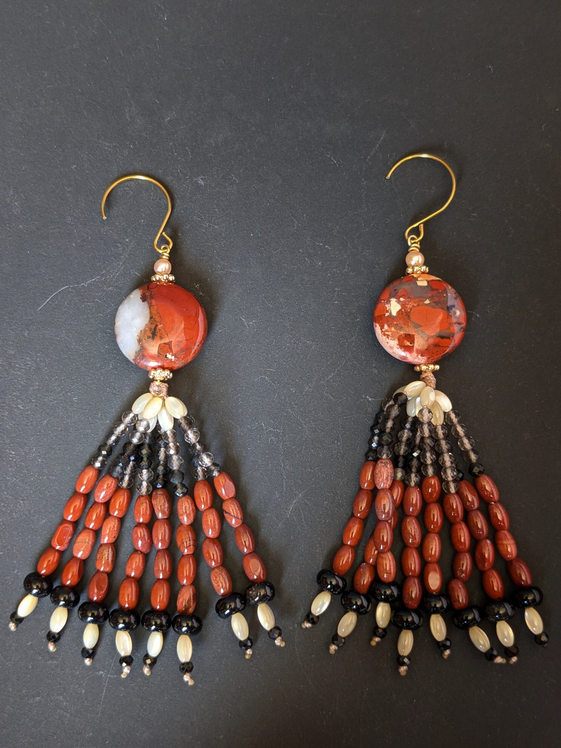 Paire de pendants d'oreilles Ojal posée à plat, jaspe rouge, quartz fumé, onyx et nacre de trochus