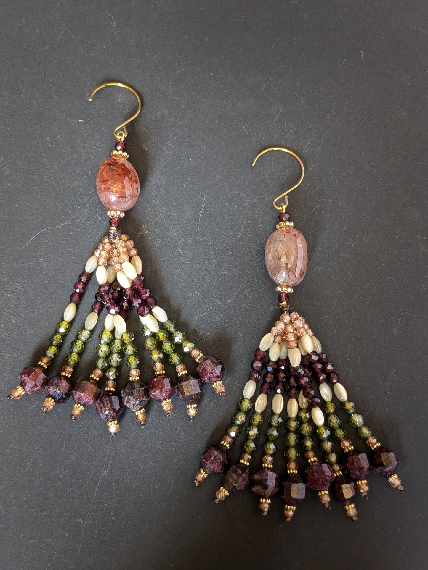 Paire de pendants d'oreilles Priya Mudra posés sur un présentoir, quartz hématoïde rosé nacré et grenats