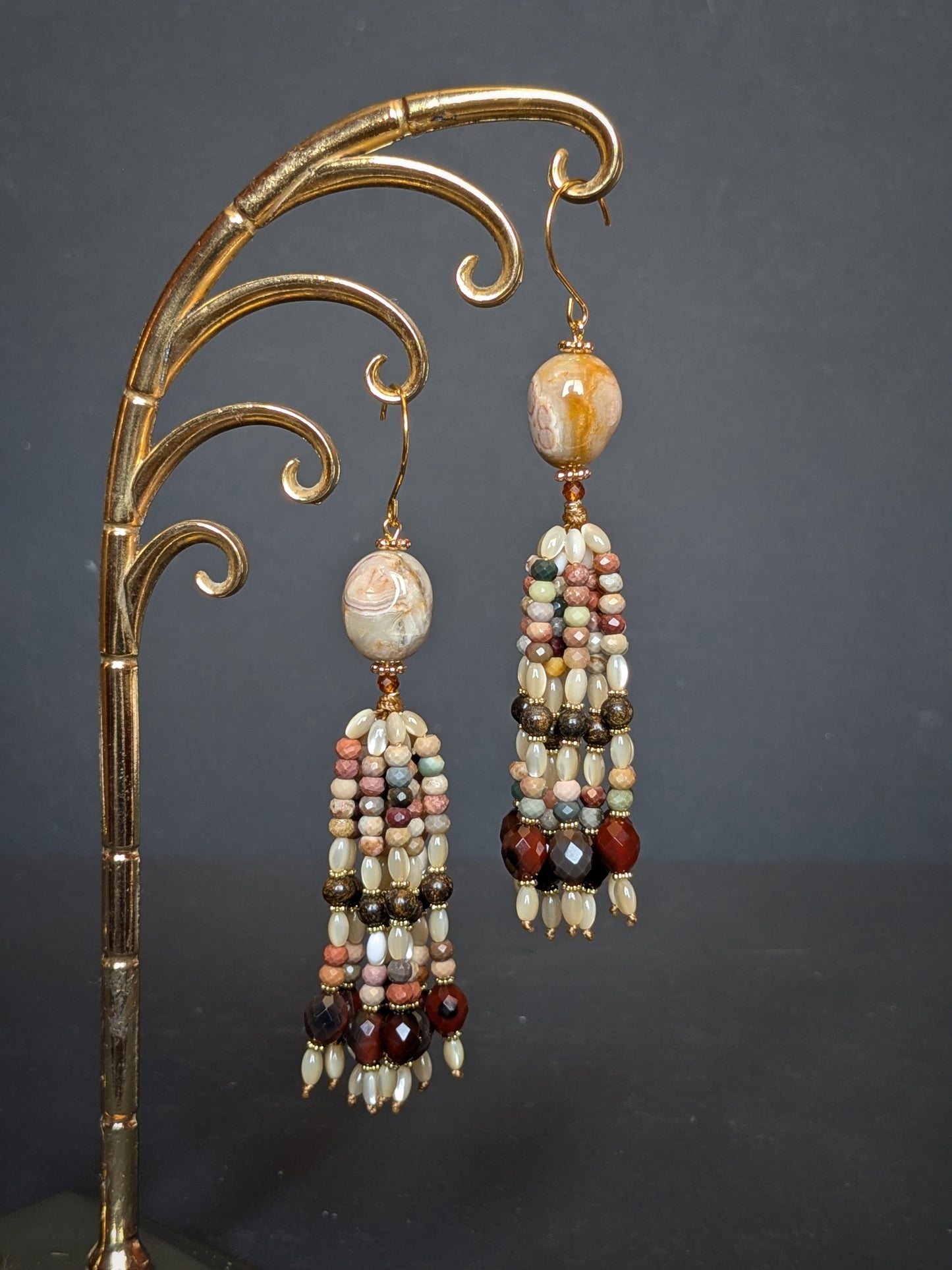 Pendants d'oreilles Riya posés sur un présentoir, camaïeu d'agate multicolore et bronzite