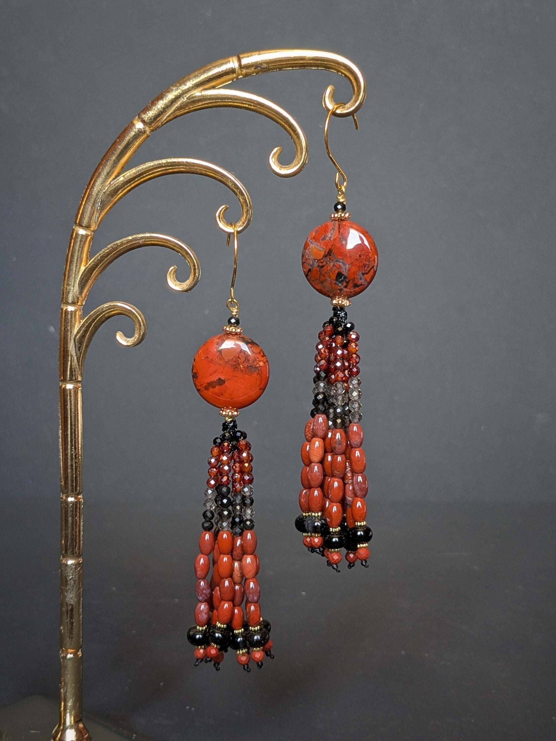 Paire de pendants d'oreilles Simran posée à plat, disque de jaspe rouge et tassel en onyx et quartz fumé