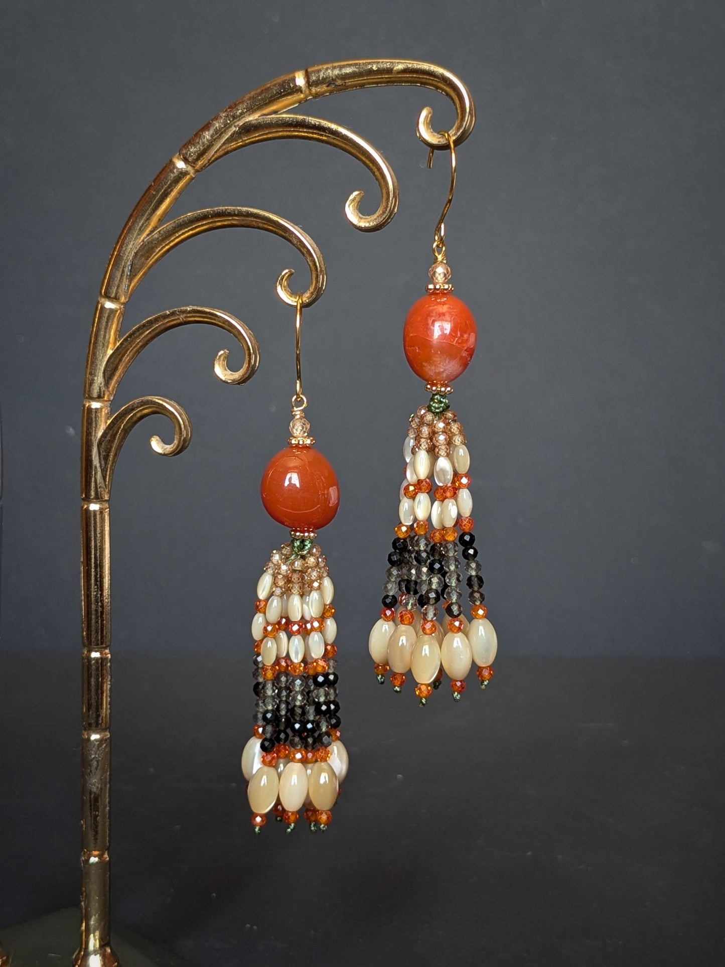 Pendants d'oreilles Zoya posés sur un présentoir, agate du Botswana orange brûlé et tassel dégradé vers le gris fumé
