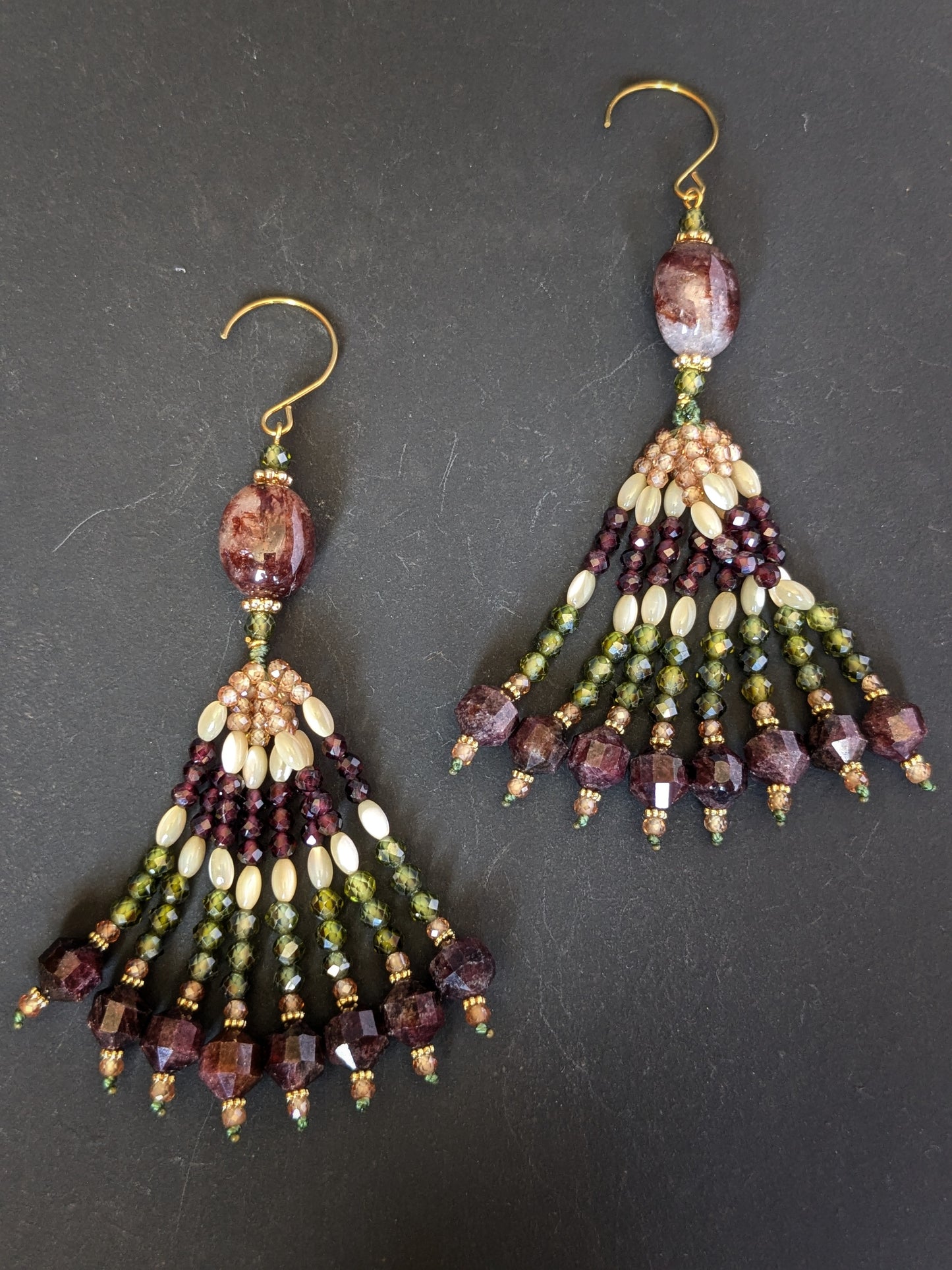 Paire de pendants d'oreilles Radhika Mudra posés sur un présentoir, quartz hématoïde et grenats