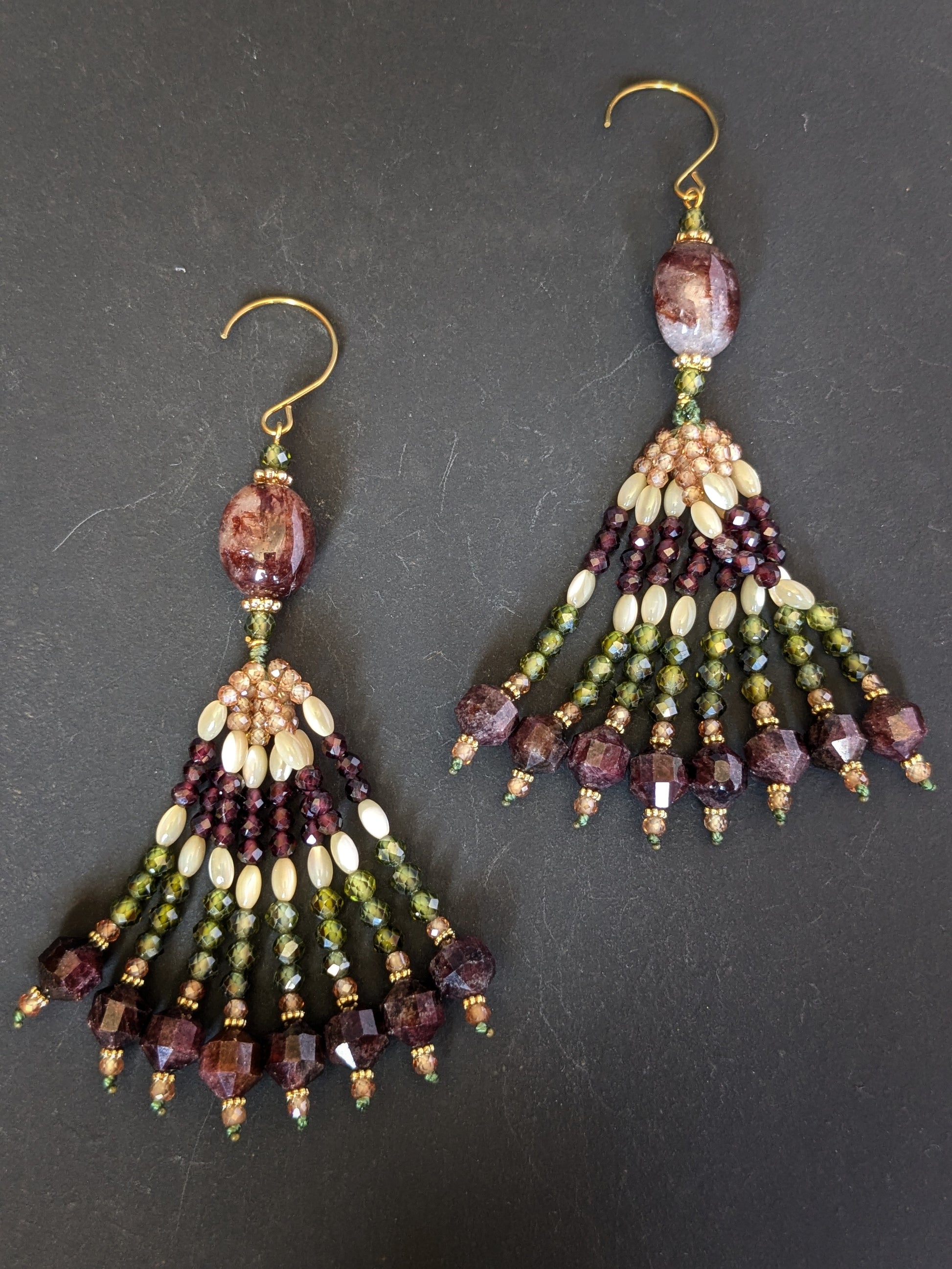 Paire de pendants d'oreilles Radhika Mudra posés sur un présentoir, quartz hématoïde et grenats