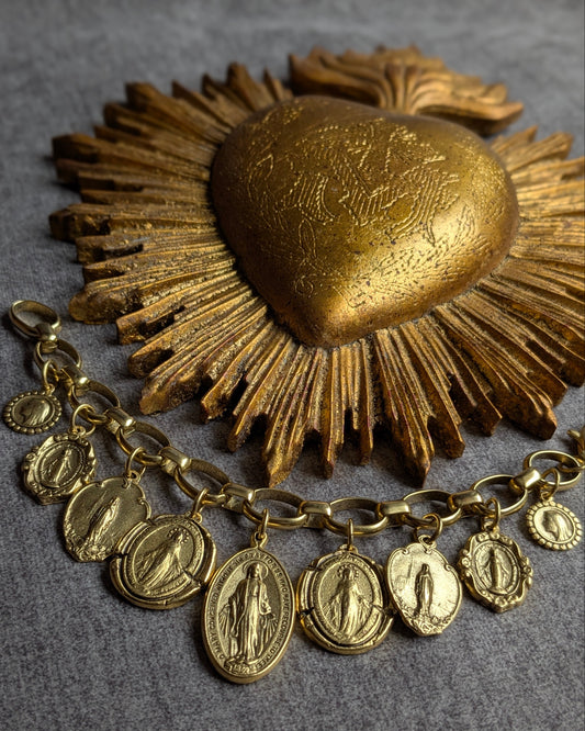 Bracelet Cantique par Mudra, une parure dorée ornée d'une accumulation de 9 charms religieux, dont 7 médailles miraculeuses réversibles sur une chaîne aux maillons ovales lisses.