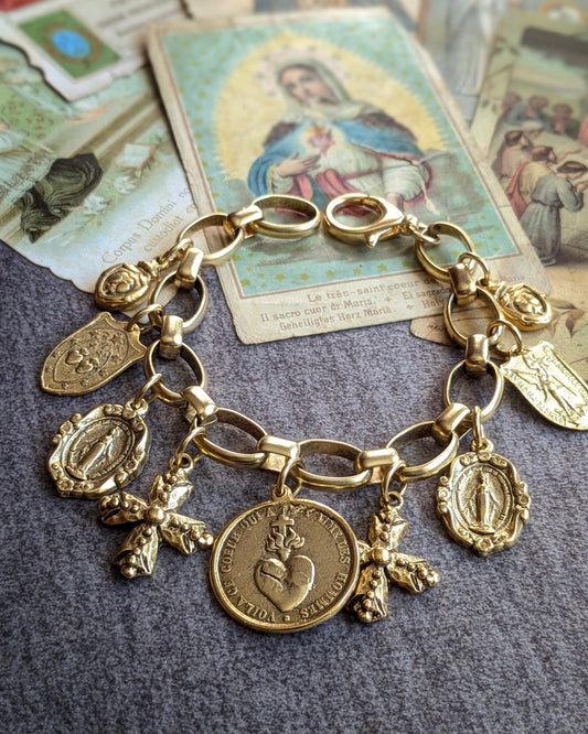 Bracelet Gloria par Mudra, une parure ex-voto au plaquage doré composée d'une accumulation de 9 médailles religieuses sur une chaîne aux maillons ovales lisses.