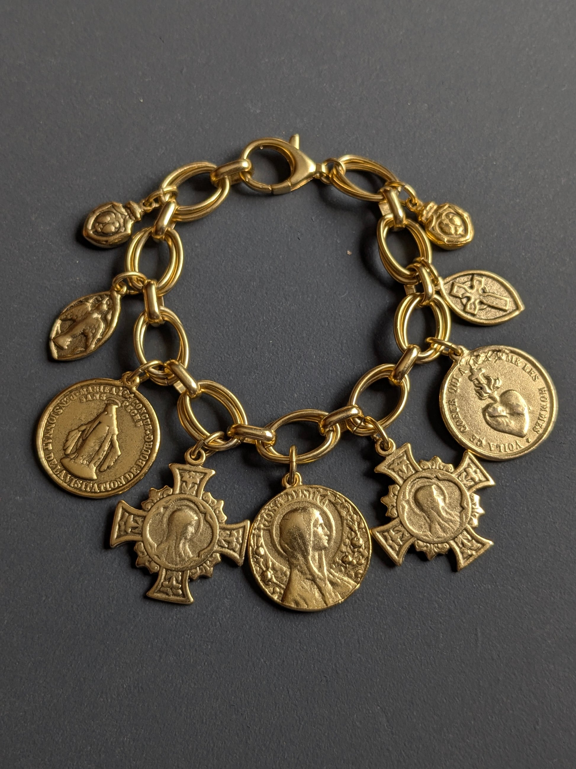 Bracelet Grâce de Mudra, accumulation dense de charms religieux dorés dans l'esprit de la collection Oh My God.