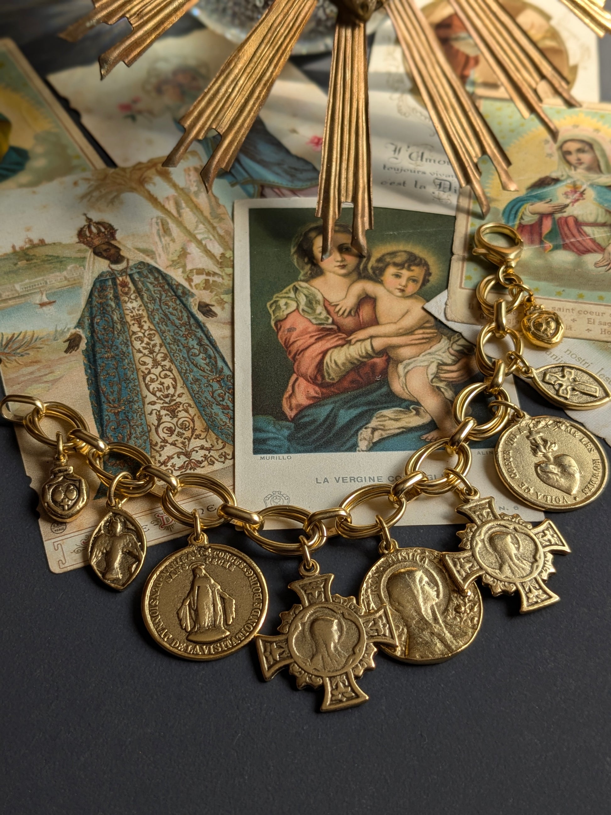 Bracelet Grâce par Mudra, une parure ex-voto au plaquage doré composée de neuf médailles religieuses réversibles sur une double maille ovale.