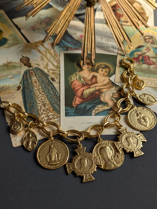 Bracelet Grâce par Mudra, une parure ex-voto au plaquage doré composée de neuf médailles religieuses réversibles sur une double maille ovale.