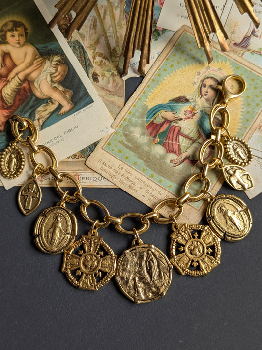 Bracelet Neuvaine par Mudra, pièce unique avec croix et colombe réversibles sur maille ovale dorée.