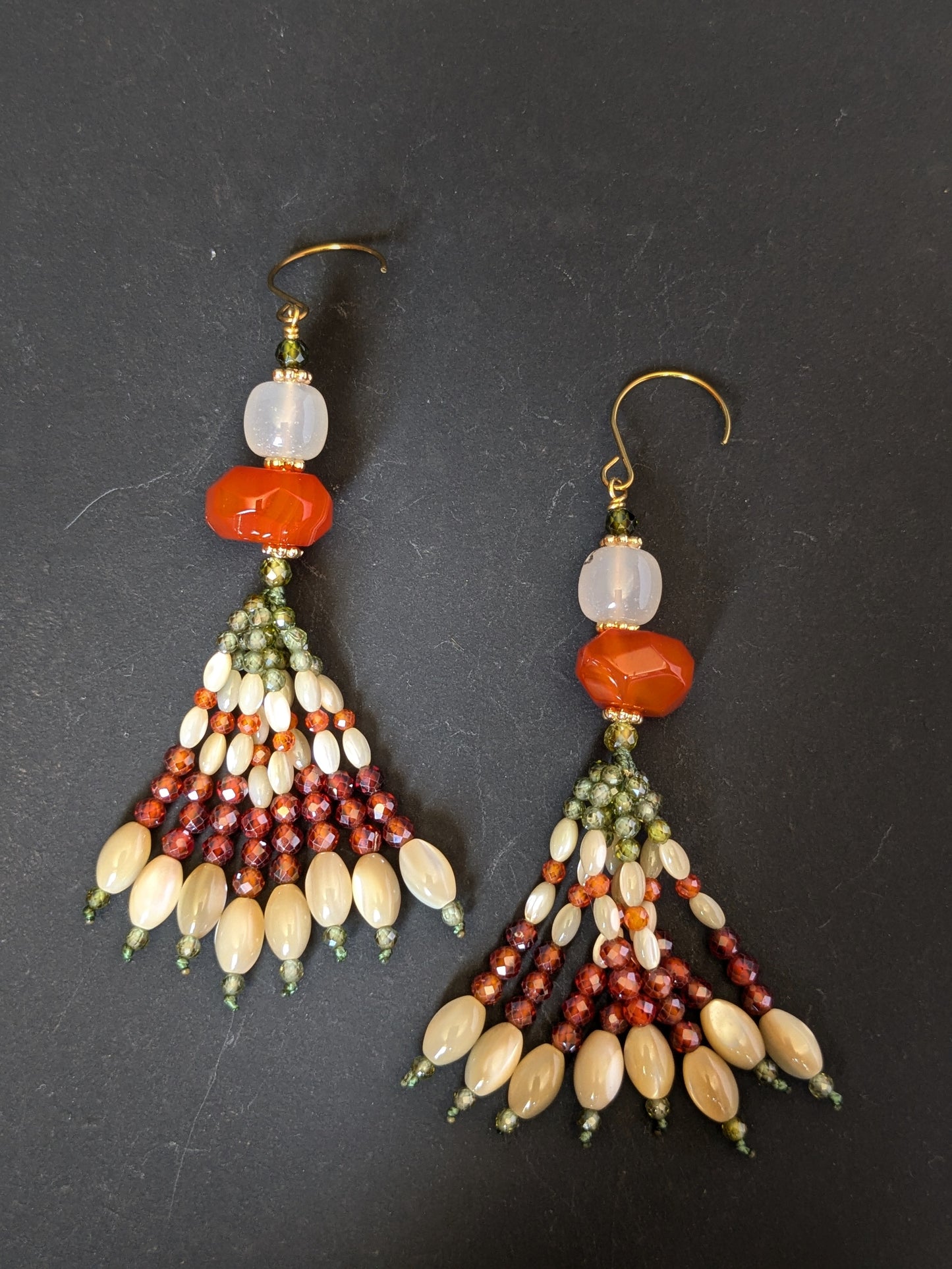 Paire de pendants d'oreilles Champa posée à plat, agate orange et blanche, zircons olive et orange et nacre de trochus