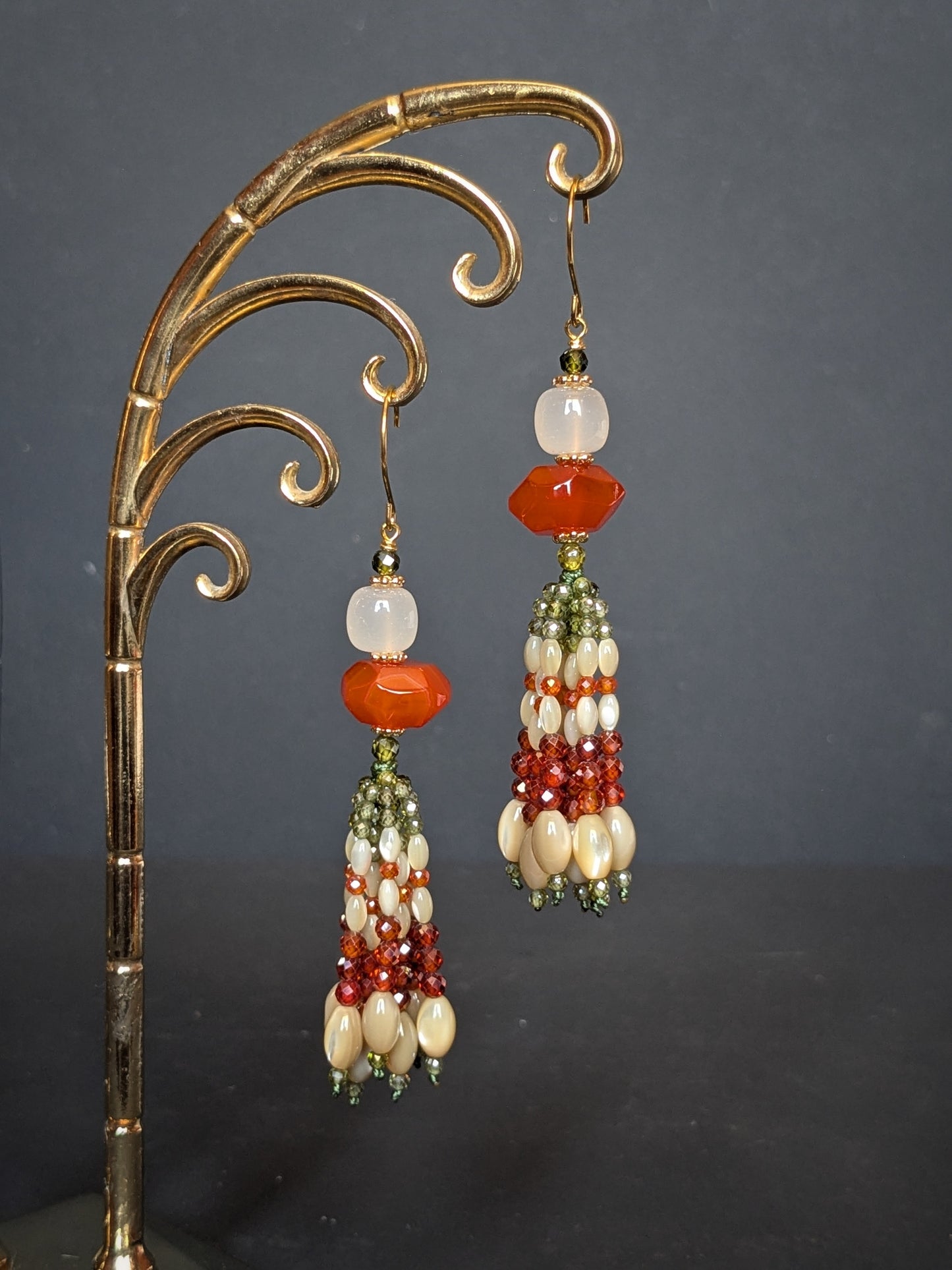 Pendants d'oreilles Champa posés sur un présentoir, agate orange et blanche, tassel en éventail olive et orange