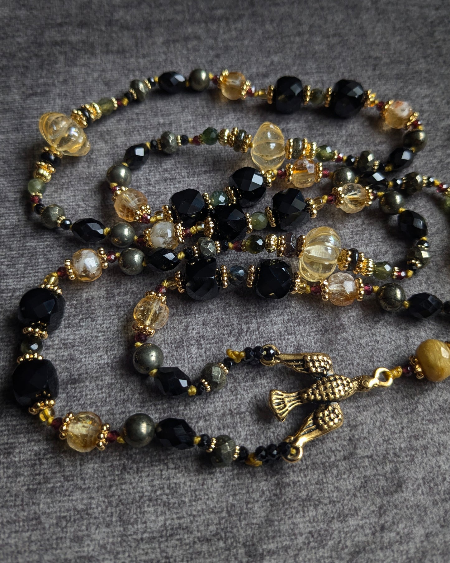 Détail des grains du chapelet : alternance de spinelle noir, pyrite métallique et quartz à rutiles dorés avec montage noué à la main.