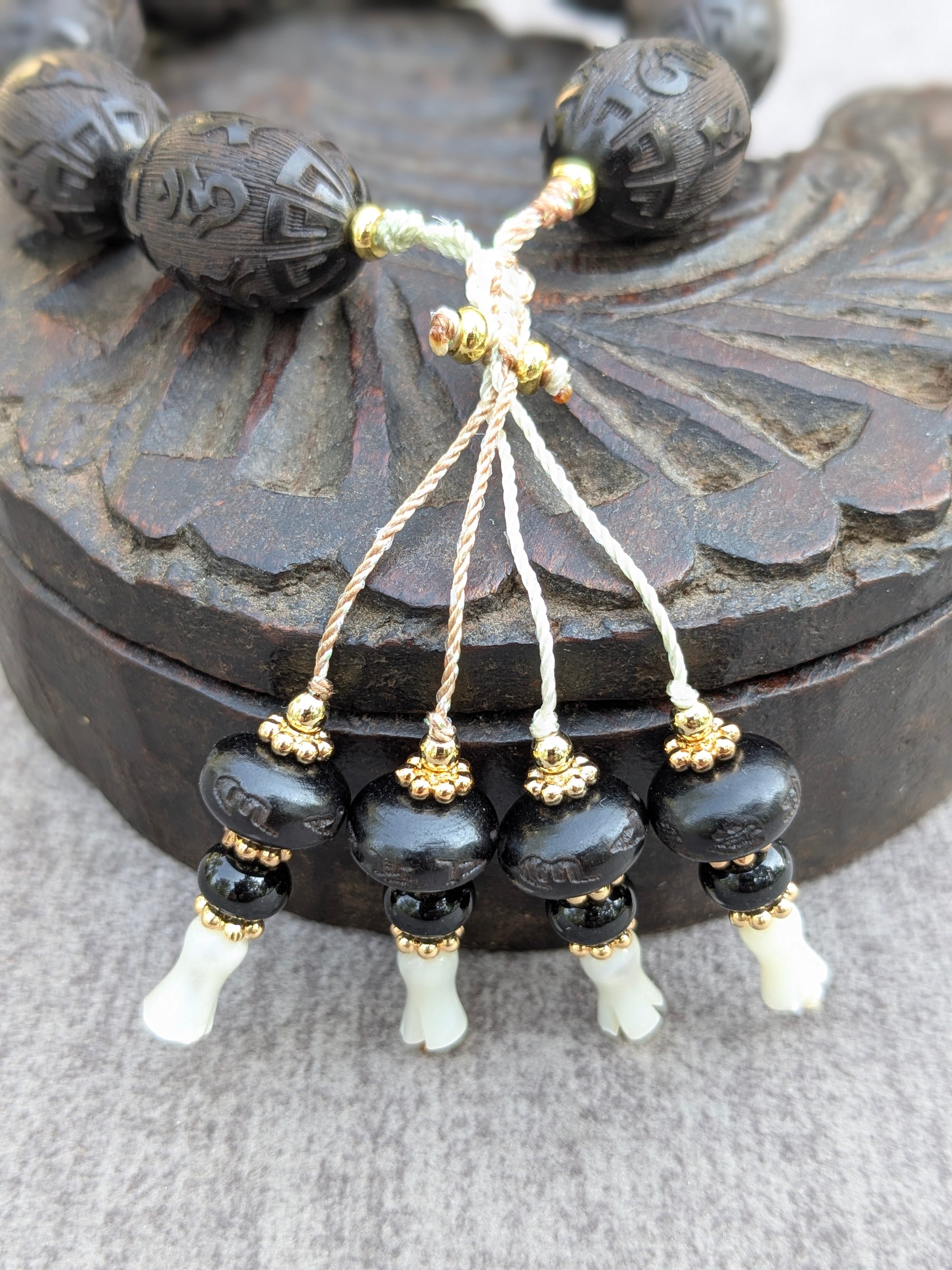 Détail des pampilles du bracelet Chenrezi Mudra en santal, onyx et nacre