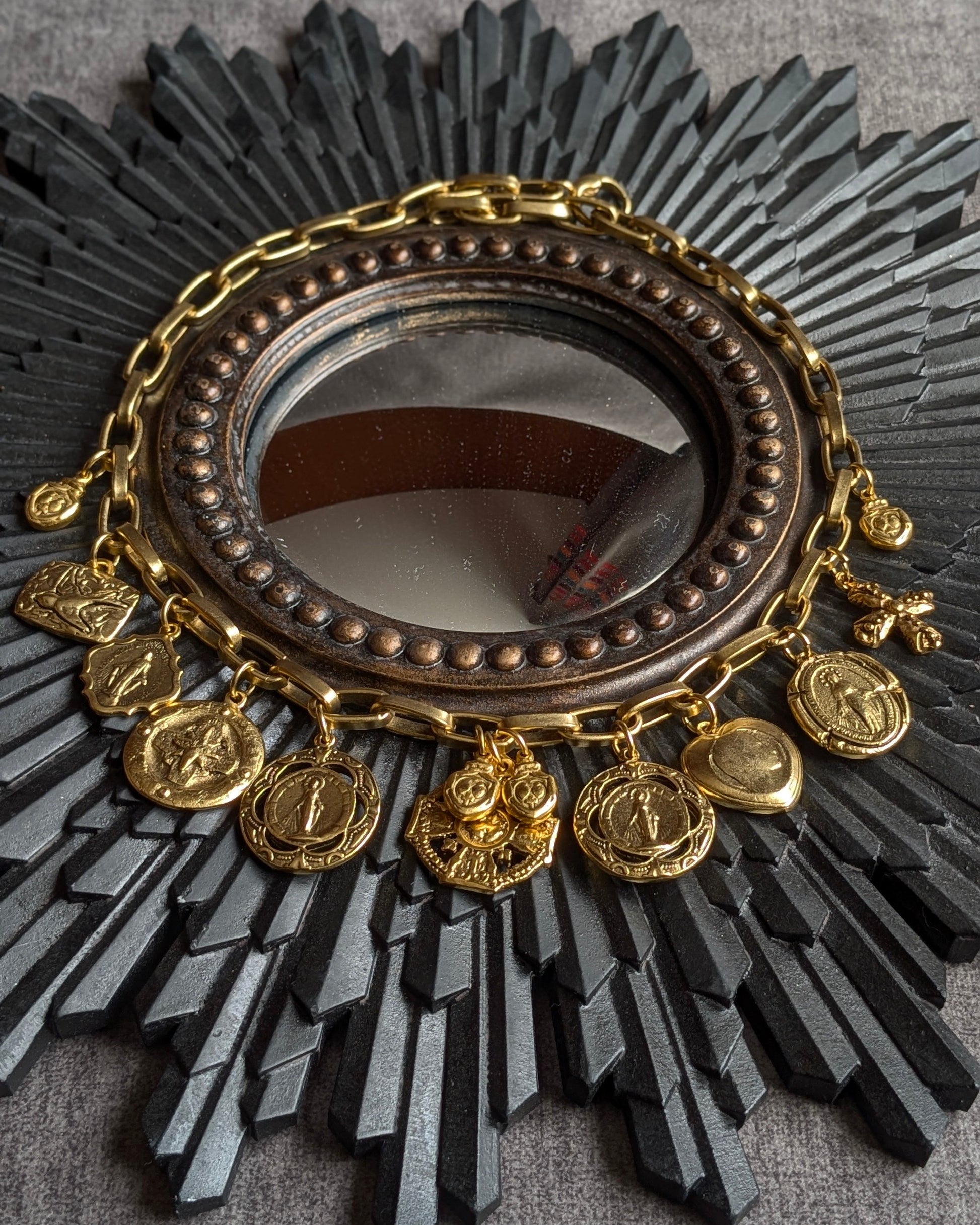Collier Miracolo par Mudra : bijou talisman avec accumulation de médailles religieuses dorées et ex-voto sur une chaîne chunky à gros maillons en laiton plaqué or.