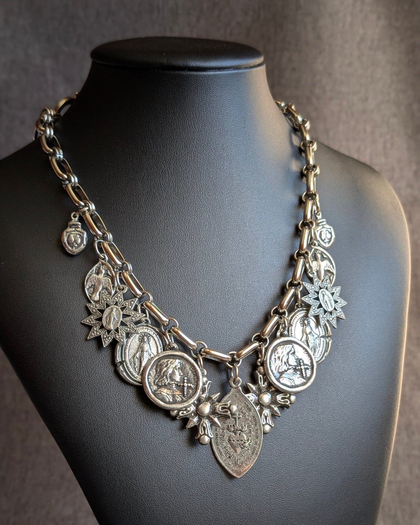 Le collier Manifesto (Oh My God), un bijou talisman unique de Mudra où 11 médailles sacrées s'accumulent pour créer une présence souveraine et protectrice.
