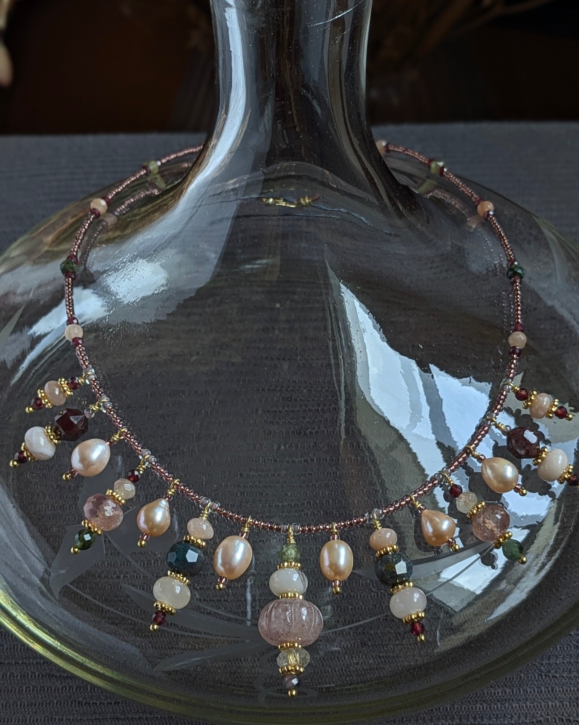 Collier Oryana présentant une structure symétrique avec quartz fraise central et breloques de pierres fines.