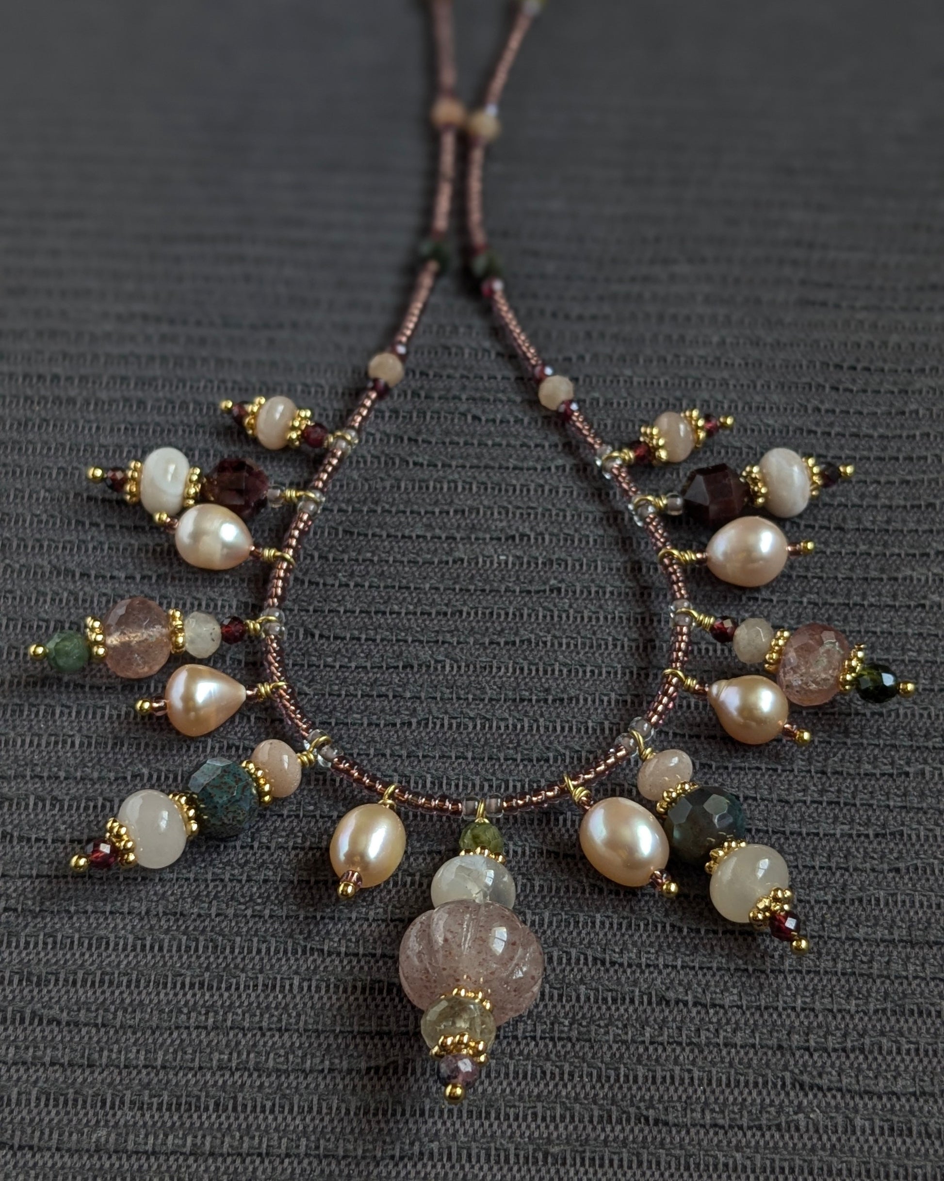 Zoom sur le quartz rutile doré et l'agate sakura poudrée montés sur fines rocailles japonaises.