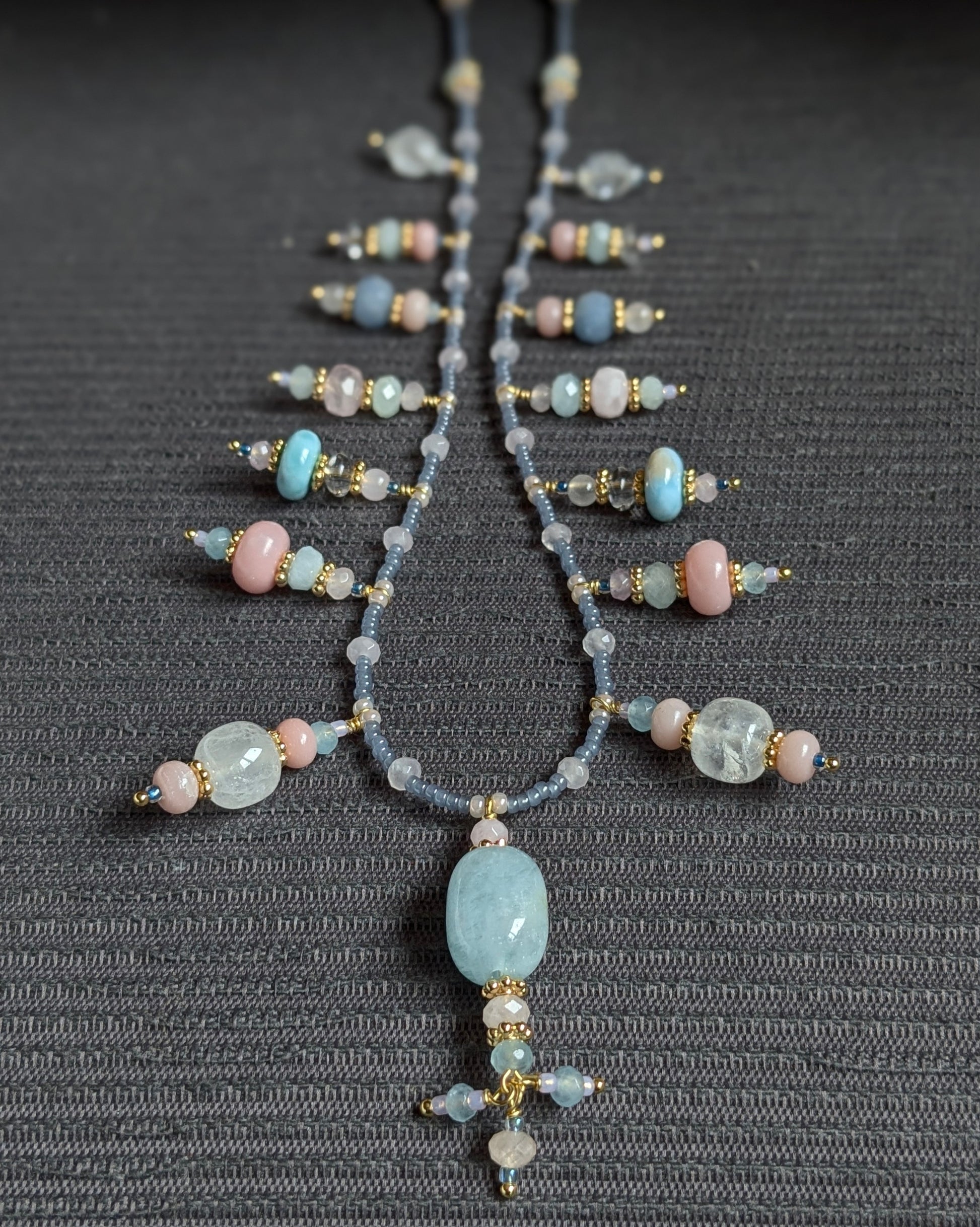 Détail rapproché des rocailles japonaises bleu givré et du jade mauve composant le collier Suryani.