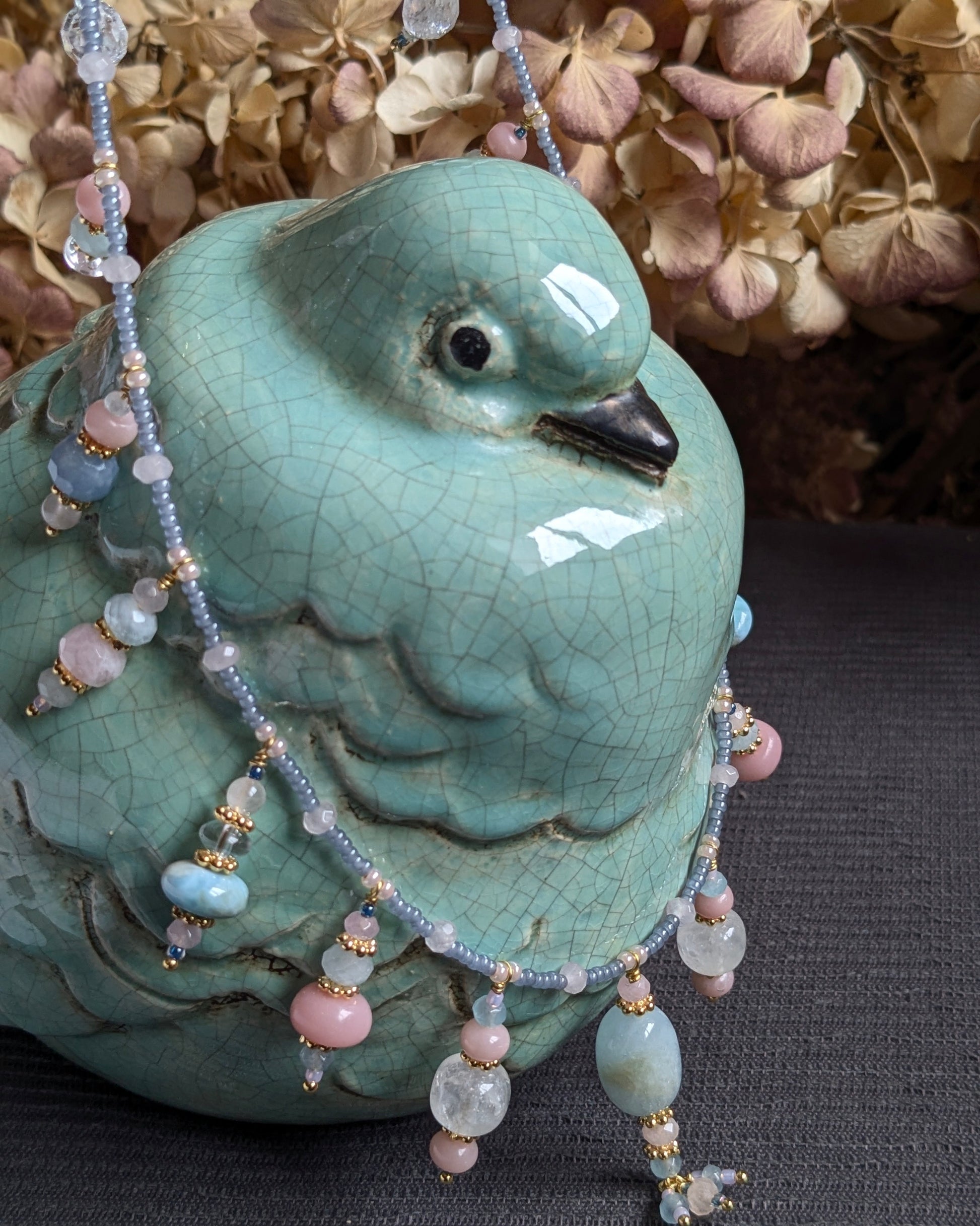 Collier Suryani de 64 cm présentant ses breloques en pierres fines bleues et ses finitions en laiton doré 18kt.