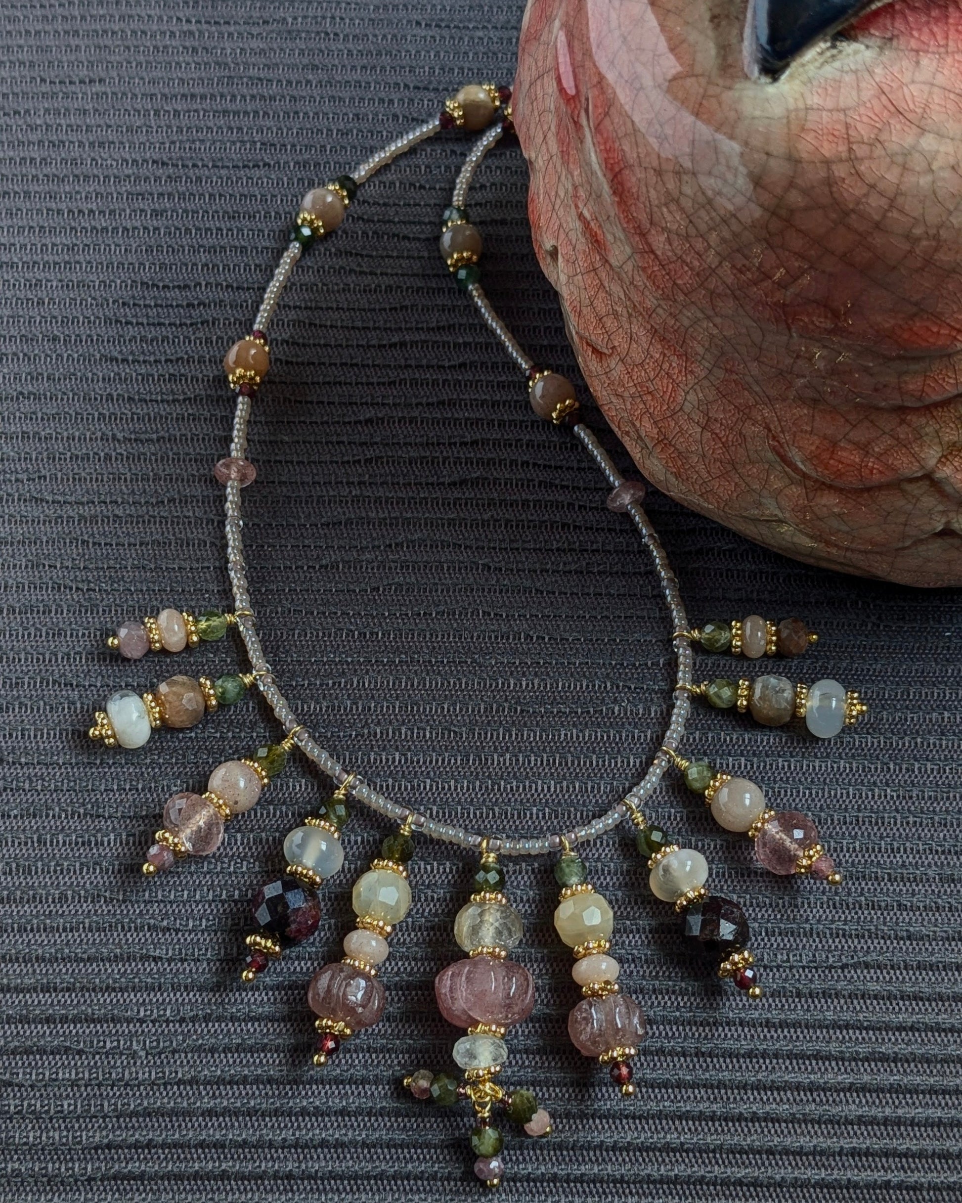 Détail des éclats du quartz rutile et de la pierre de lune pêche sur le collier Kaivani.