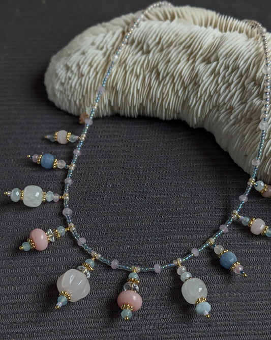 Collier Tanisha 54 cm en pierres fines : quartz rose sculpté, opale rose, aventurine bleue, aigue-marine, cristal de roche, jade mauve, avec rocailles japonaises irisées bleues