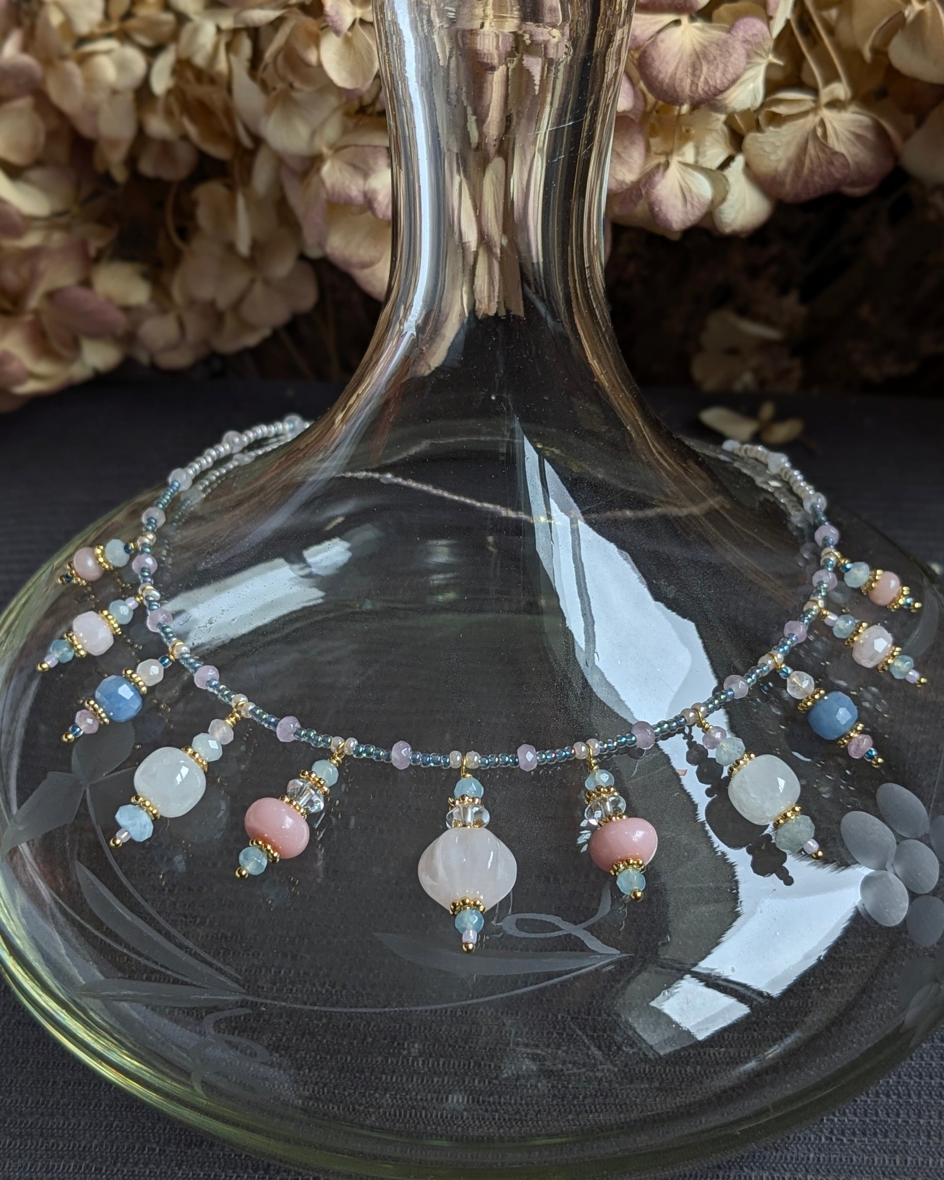 Focus sur les reflets irisés de l'opale rose et les rocailles japonaises bleues du collier Tanisha.