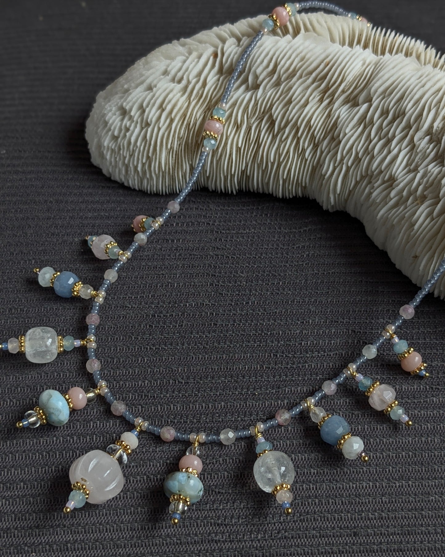Zoom sur le quartz rose sculpté et les rocailles japonaises scintillantes du collier Prishaara.